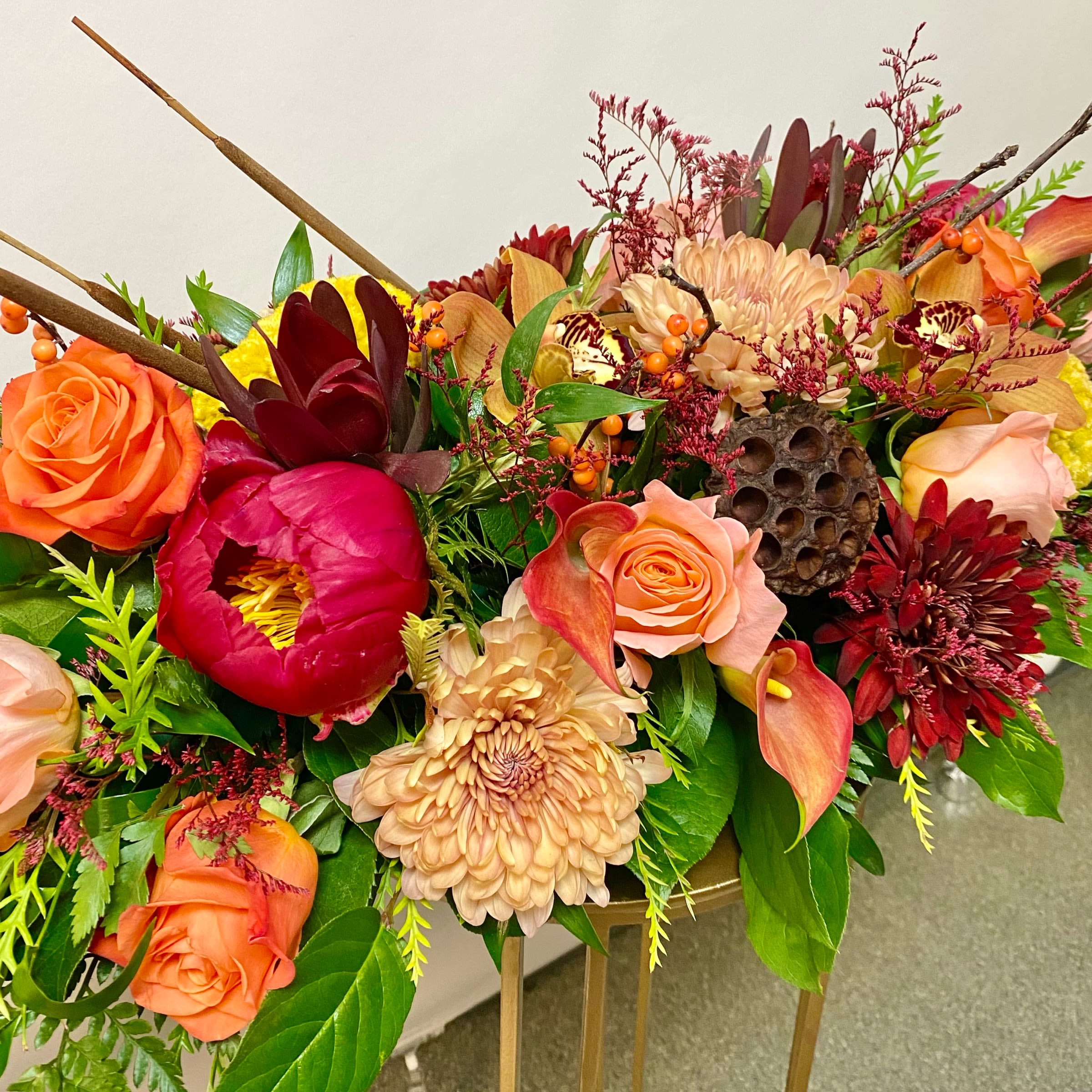 Colorful floral arrangement with roses, chrysanthemums, and calla lilies in a low container