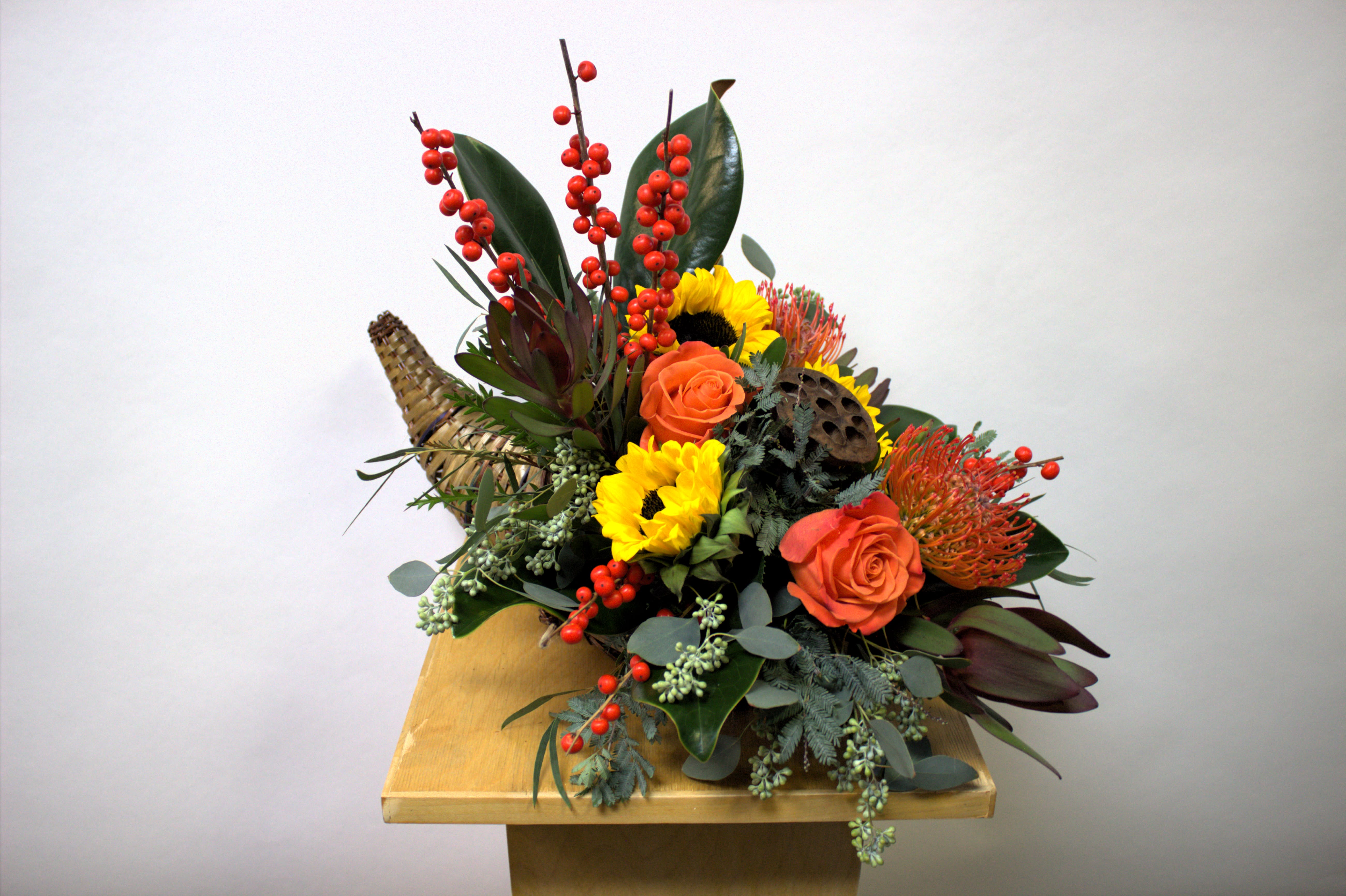 Mixed floral arrangement with sunflowers, orange roses, and red berry stems