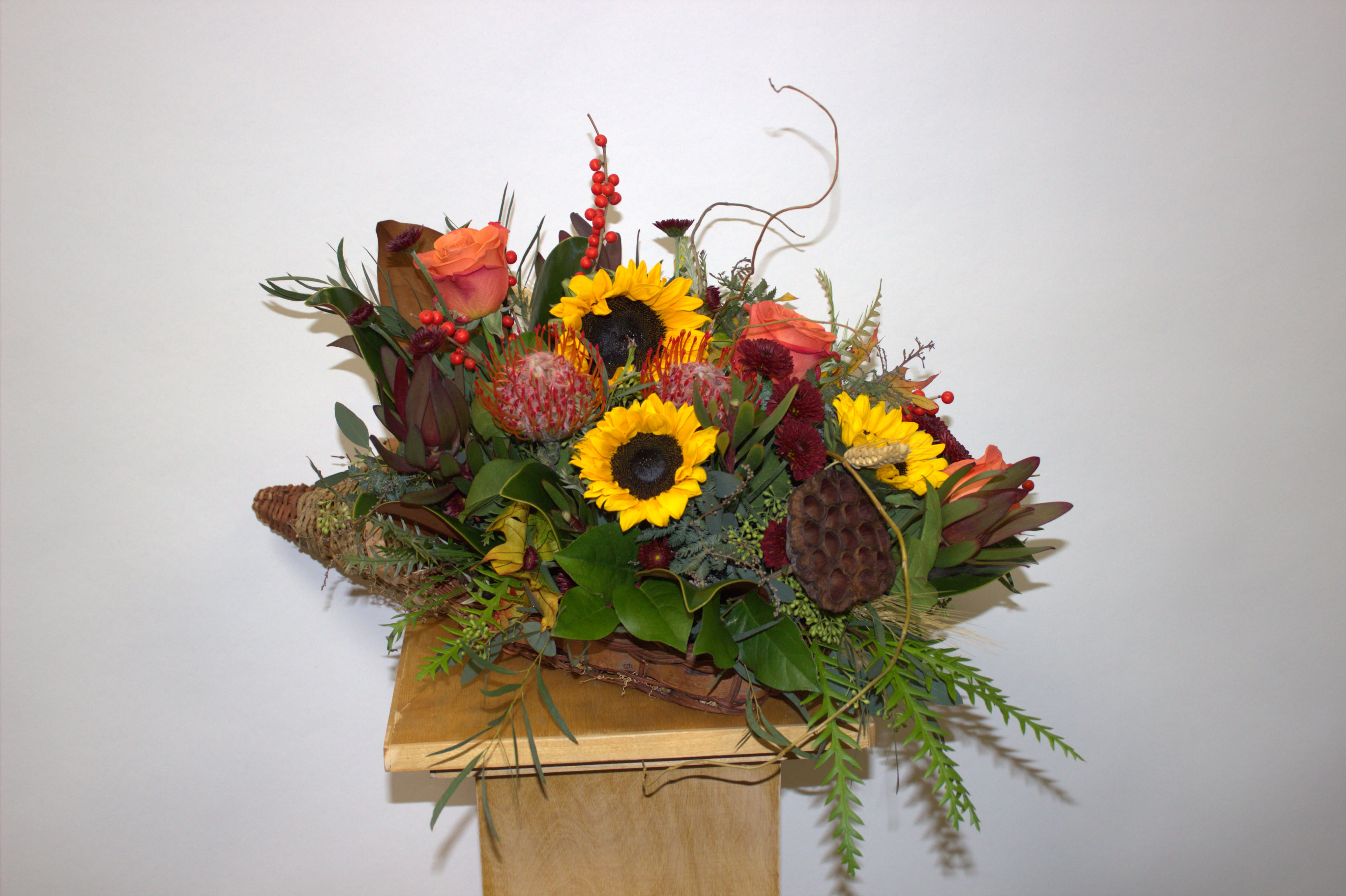 Mixed bouquet with sunflowers and orange roses in a woven basket