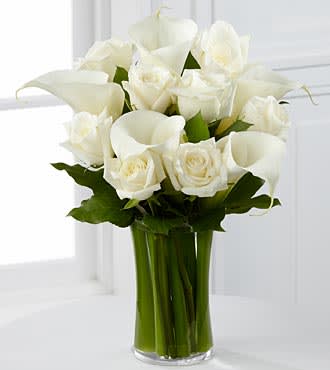 White roses and calla lilies in a clear glass vase