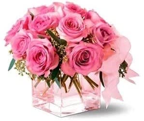 Pink roses arranged in a clear square vase with a pink ribbon