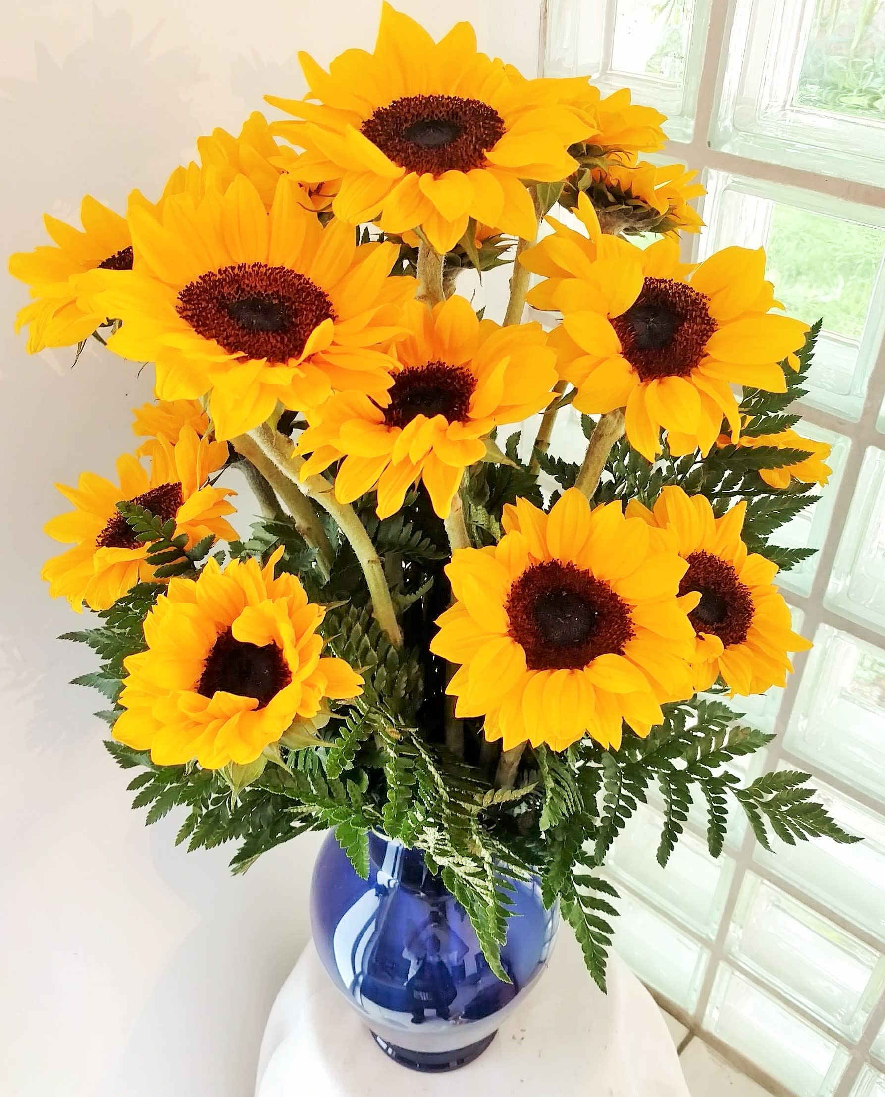 Bouquet of bright yellow sunflowers in a blue vase