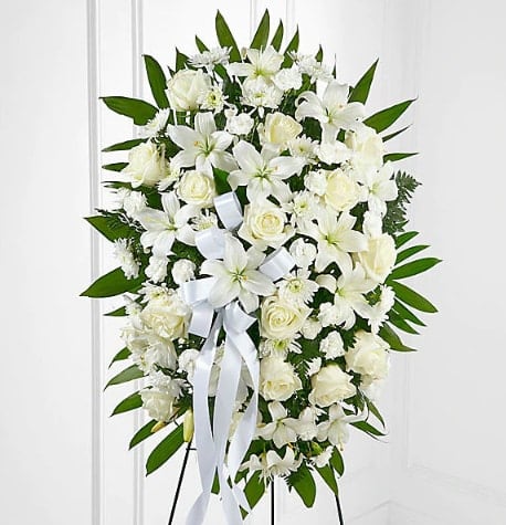 White floral standing spray with roses and lilies on an easel