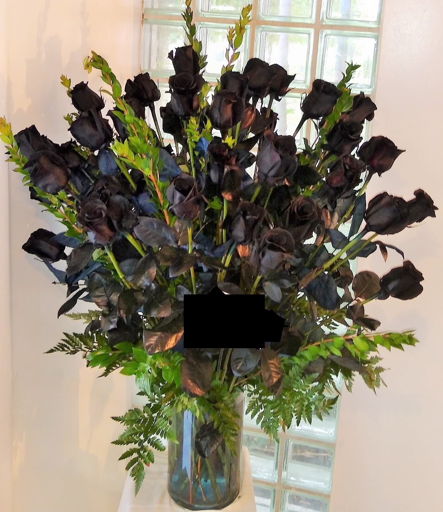 Tall bouquet of black roses in a glass vase