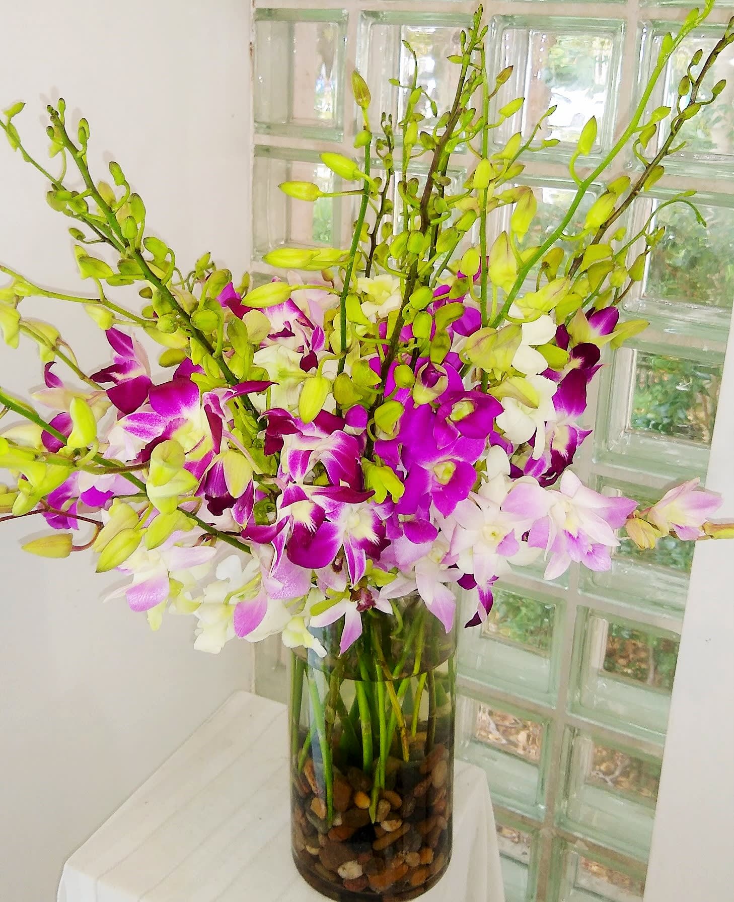 Tall vase arrangement of purple, white, and pale pink orchids