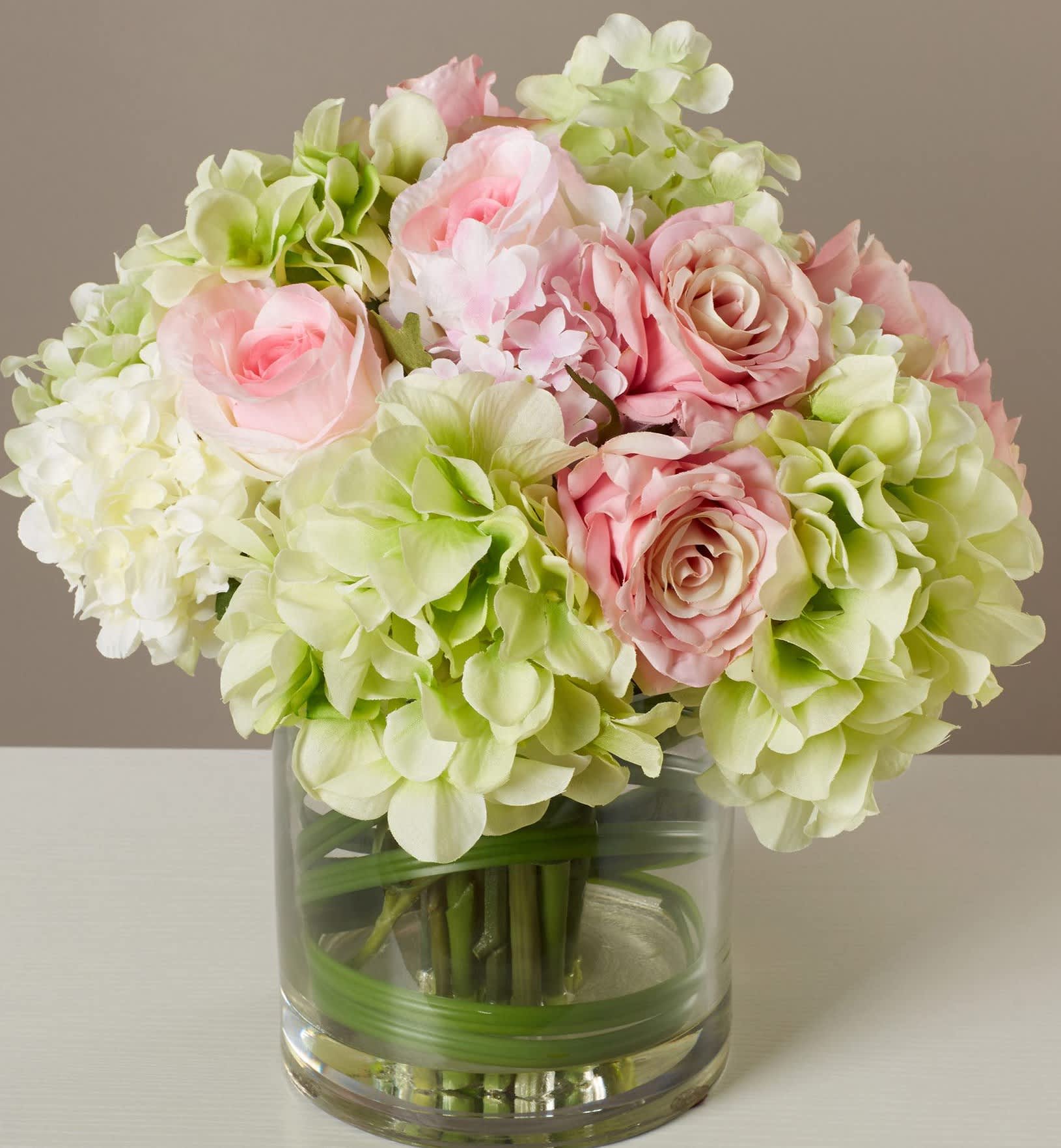 Pink roses and pale green hydrangeas in a clear glass vase