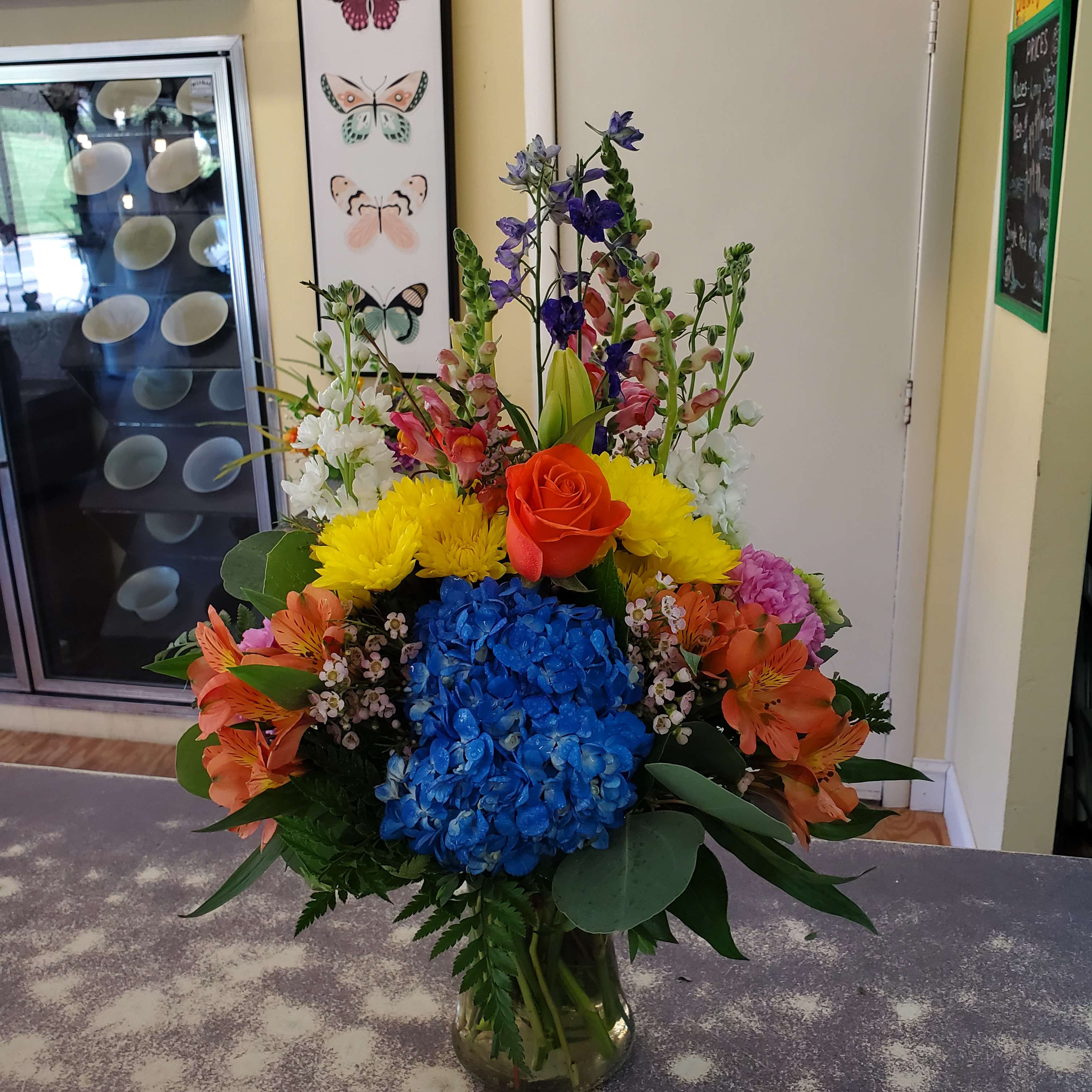 Colorful mixed bouquet in a glass vase with hydrangea, roses, and lilies