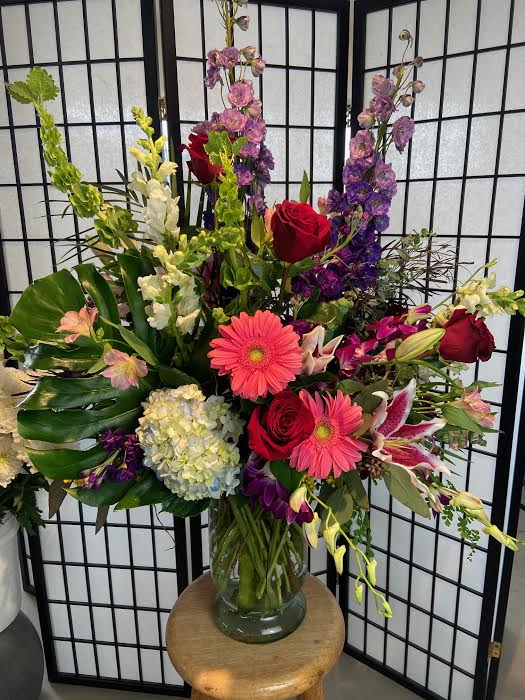 Mixed bouquet in a glass vase with red roses, pink gerberas, and purple flowers