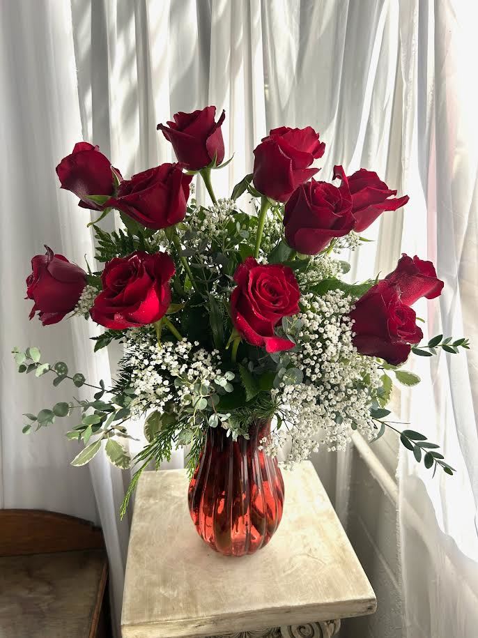 Red roses in a red glass vase with white filler flowers