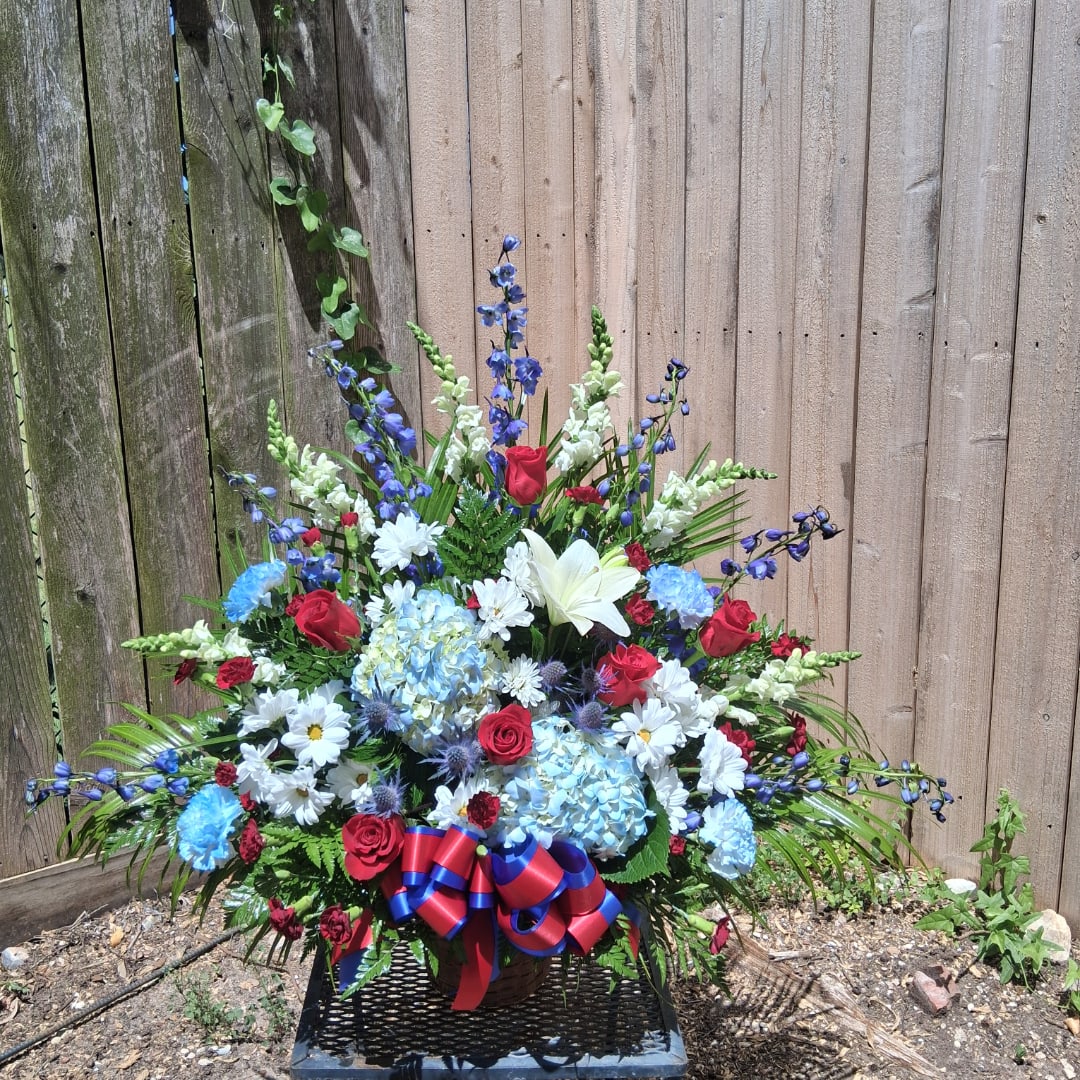 Large mixed flower arrangement in a basket with red, blue, and white blooms