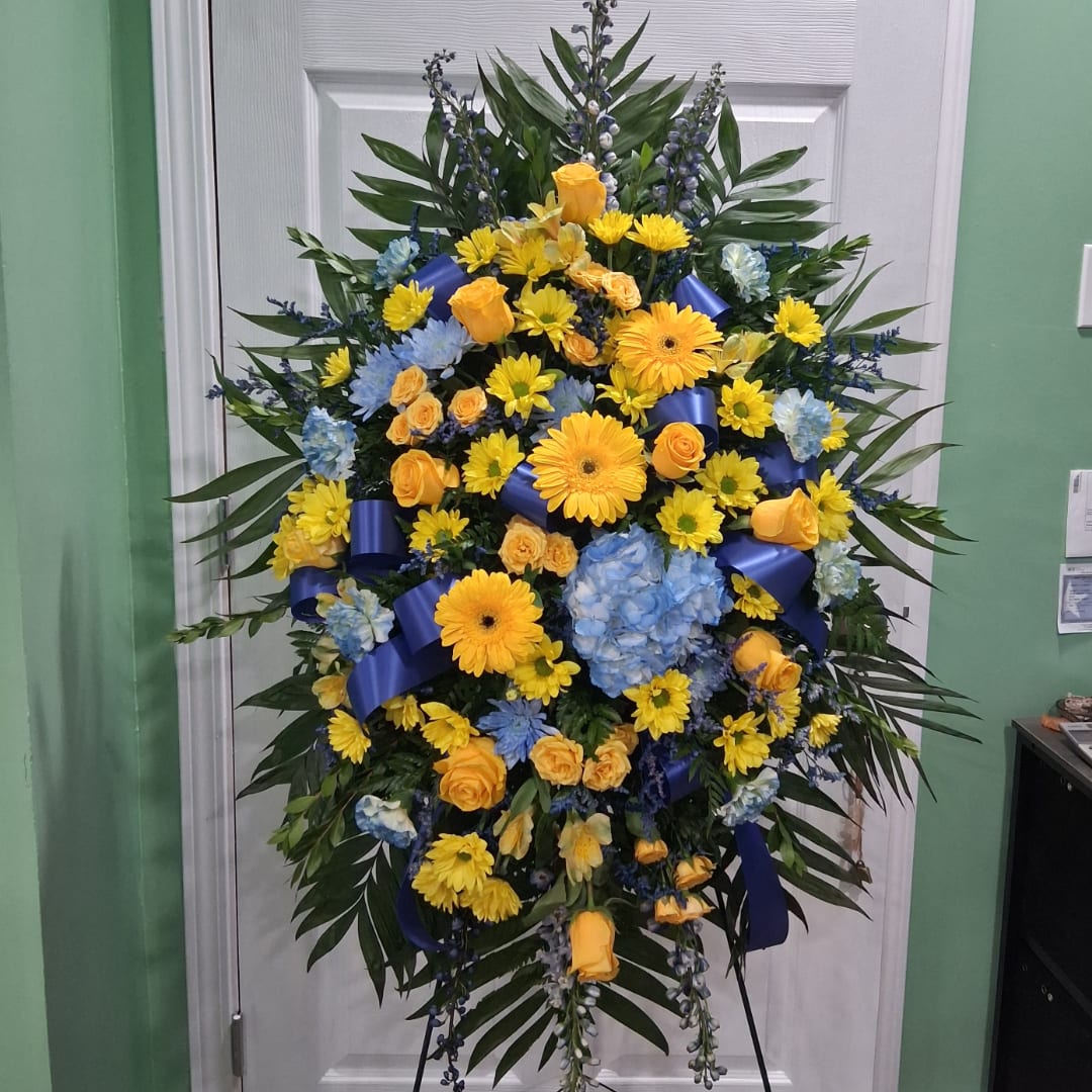 Large standing spray of yellow, blue, and orange flowers on a stand