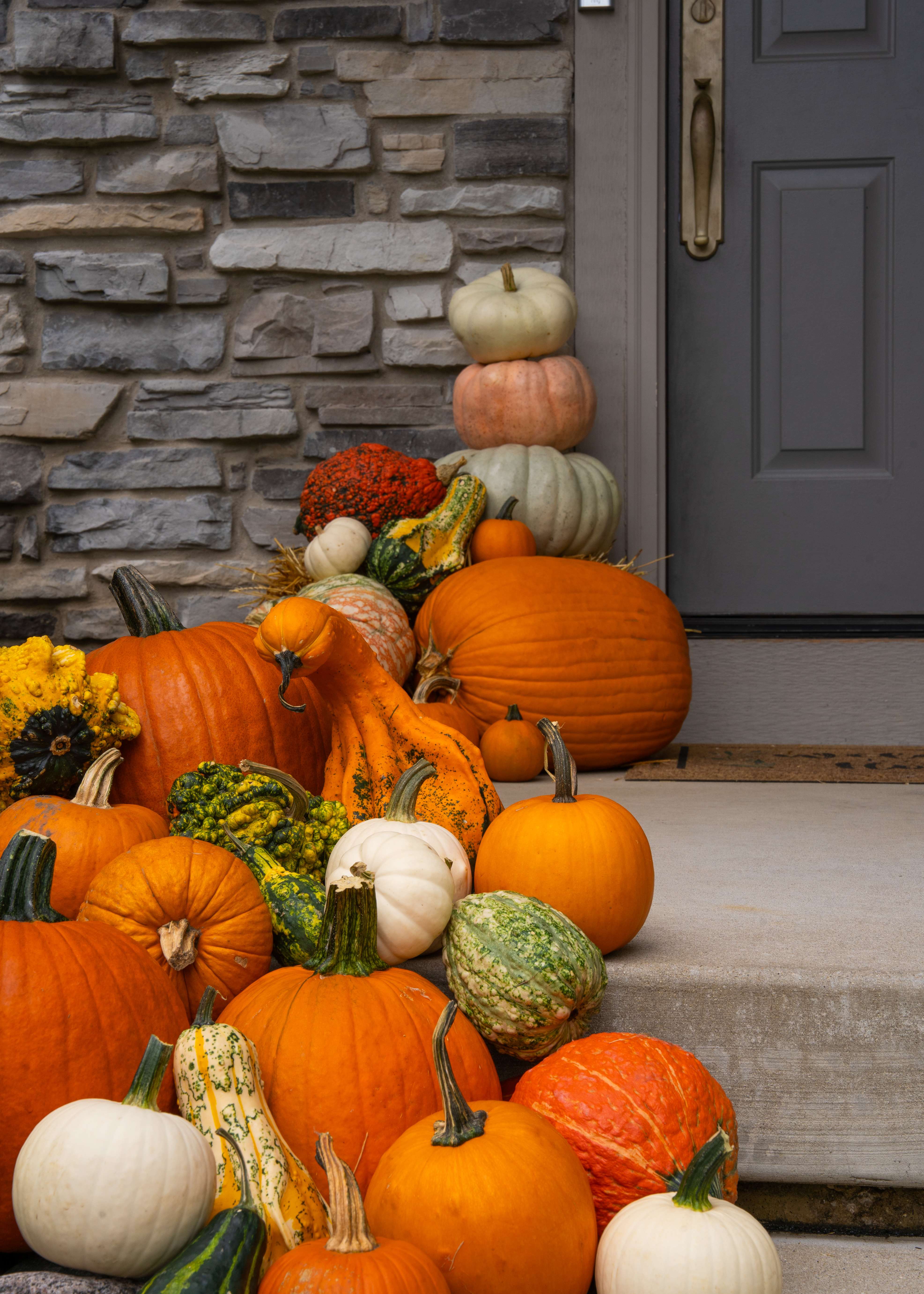 Stacked pumpkins and gourds arranged by a front door