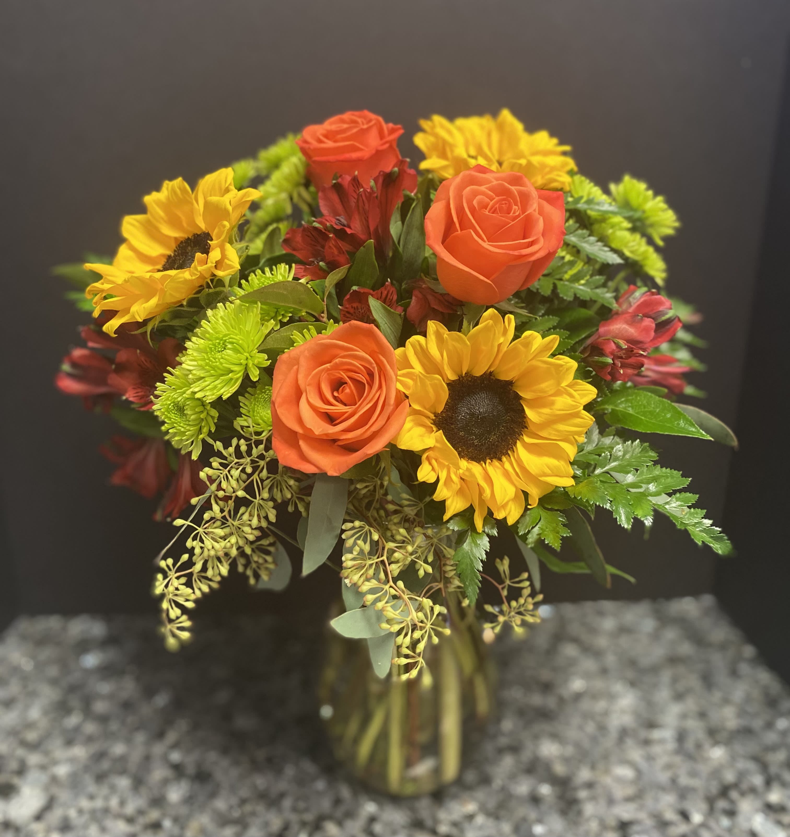 Bouquet of orange roses and yellow sunflowers in a glass vase