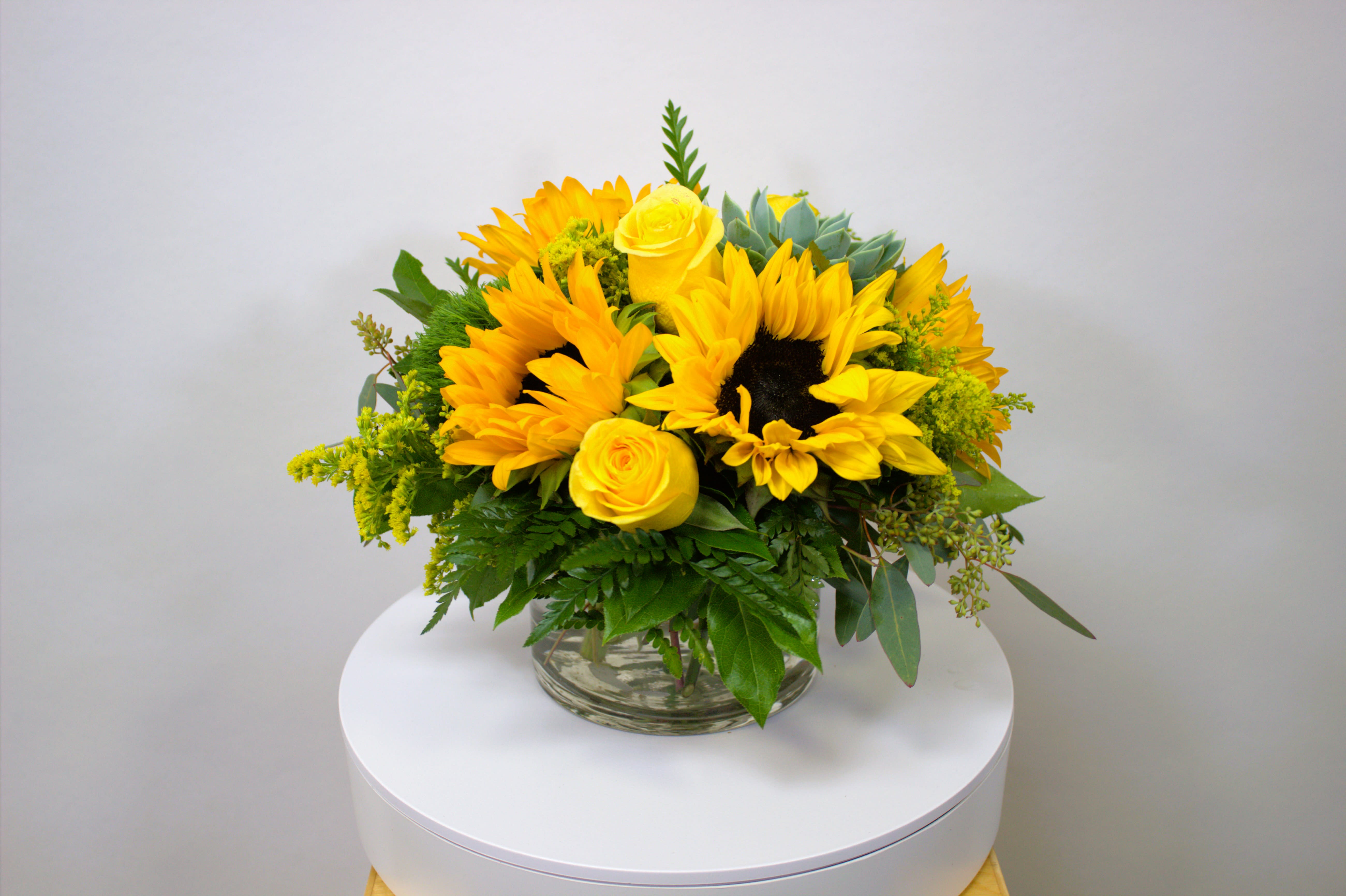 Yellow sunflower and rose arrangement in a clear glass vase