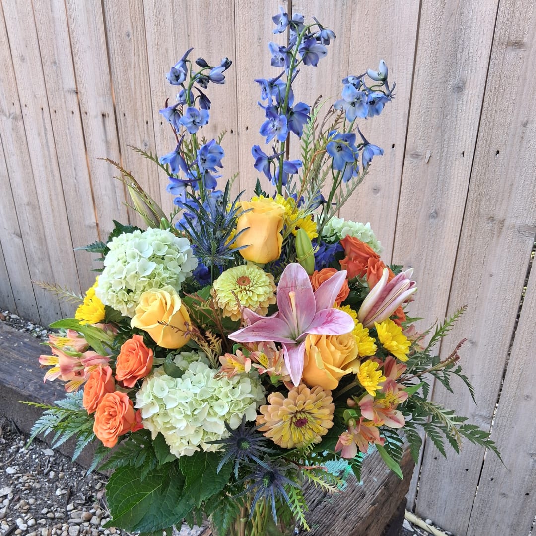 Colorful mixed bouquet with roses, lilies, hydrangeas, and blue delphinium