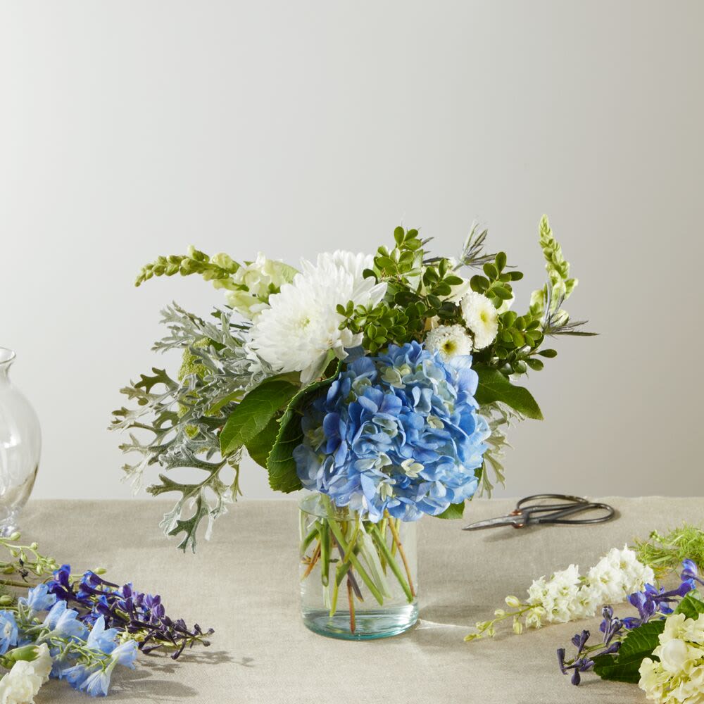 Blue hydrangea and white flowers in a clear glass vase