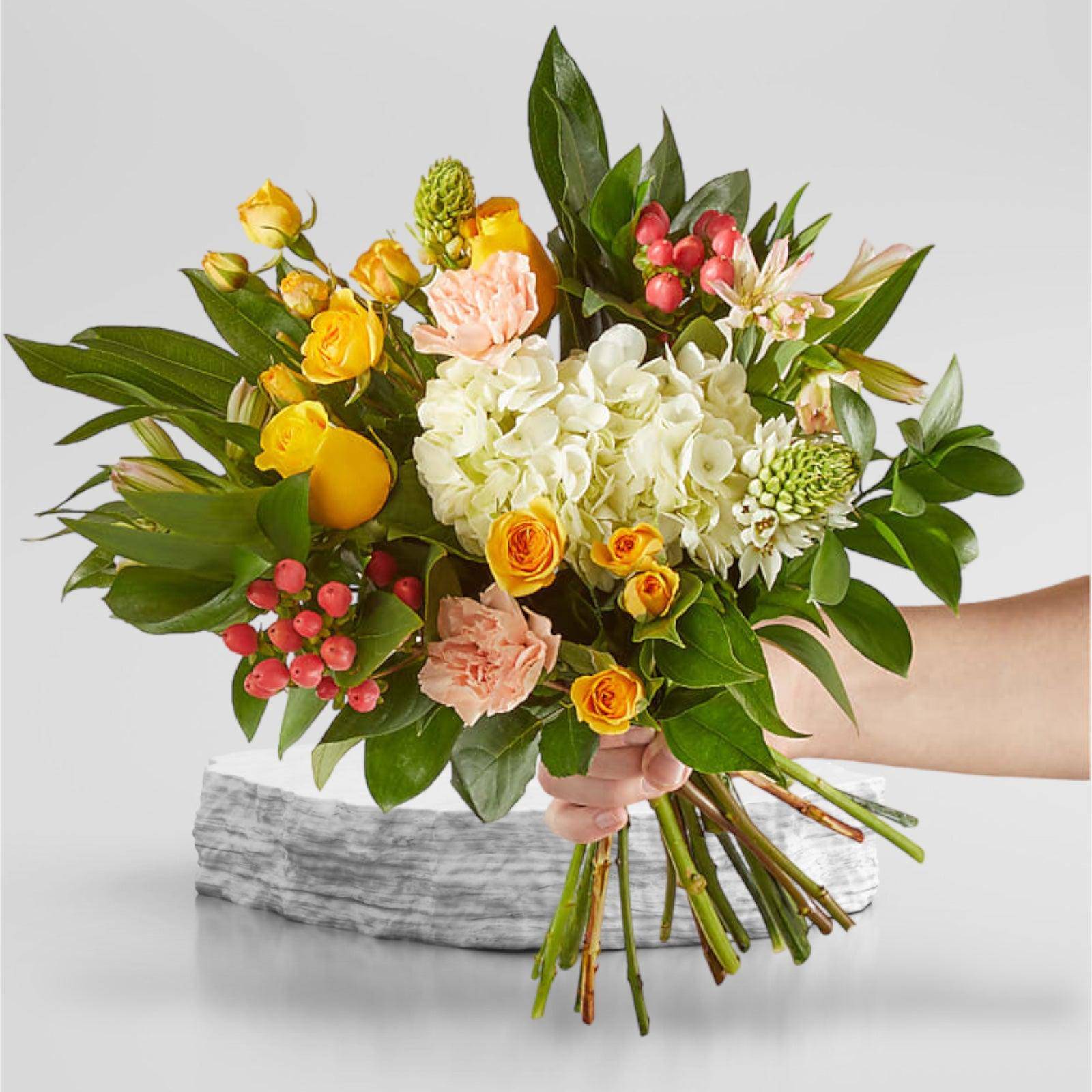 Handheld bouquet of yellow and peach flowers with white hydrangea