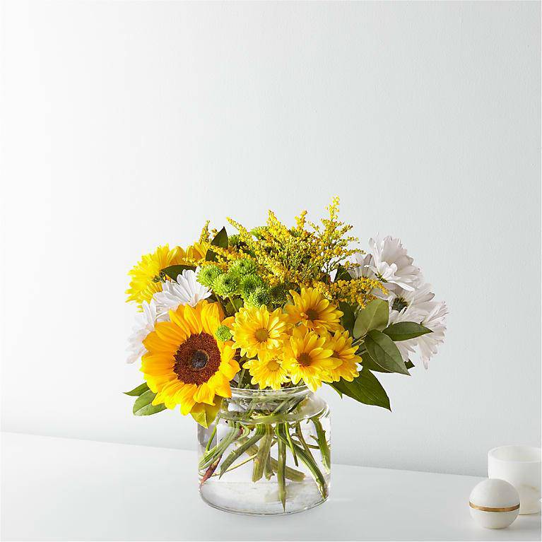 Yellow and white flowers arranged in a clear glass vase