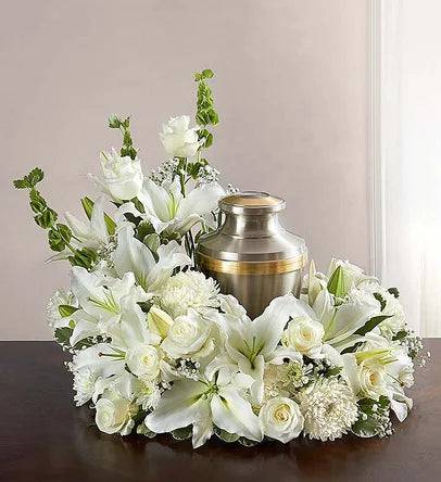 White floral funeral arrangement around a metal urn