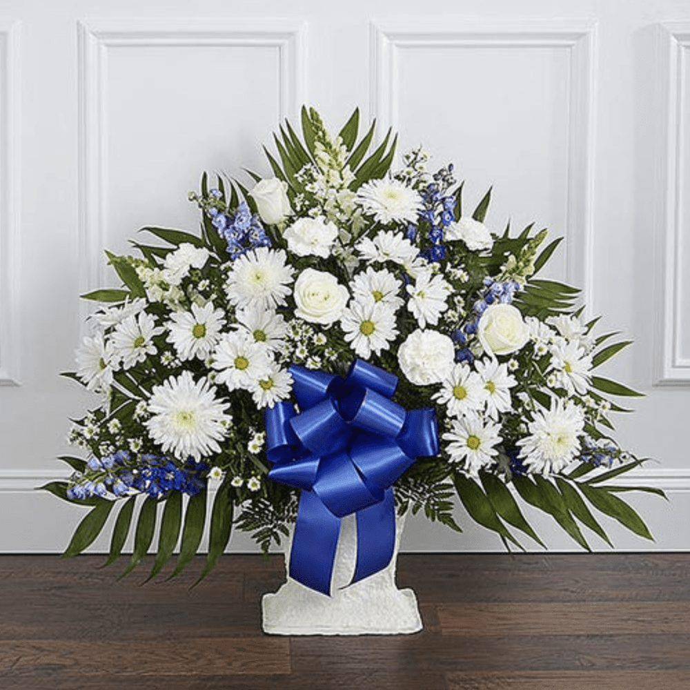 White floral standing spray with a blue ribbon on a pedestal base