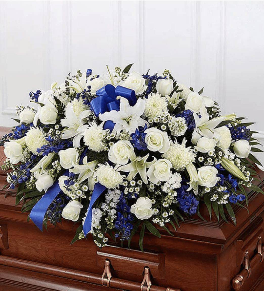 White and blue floral casket spray with ribbon accents
