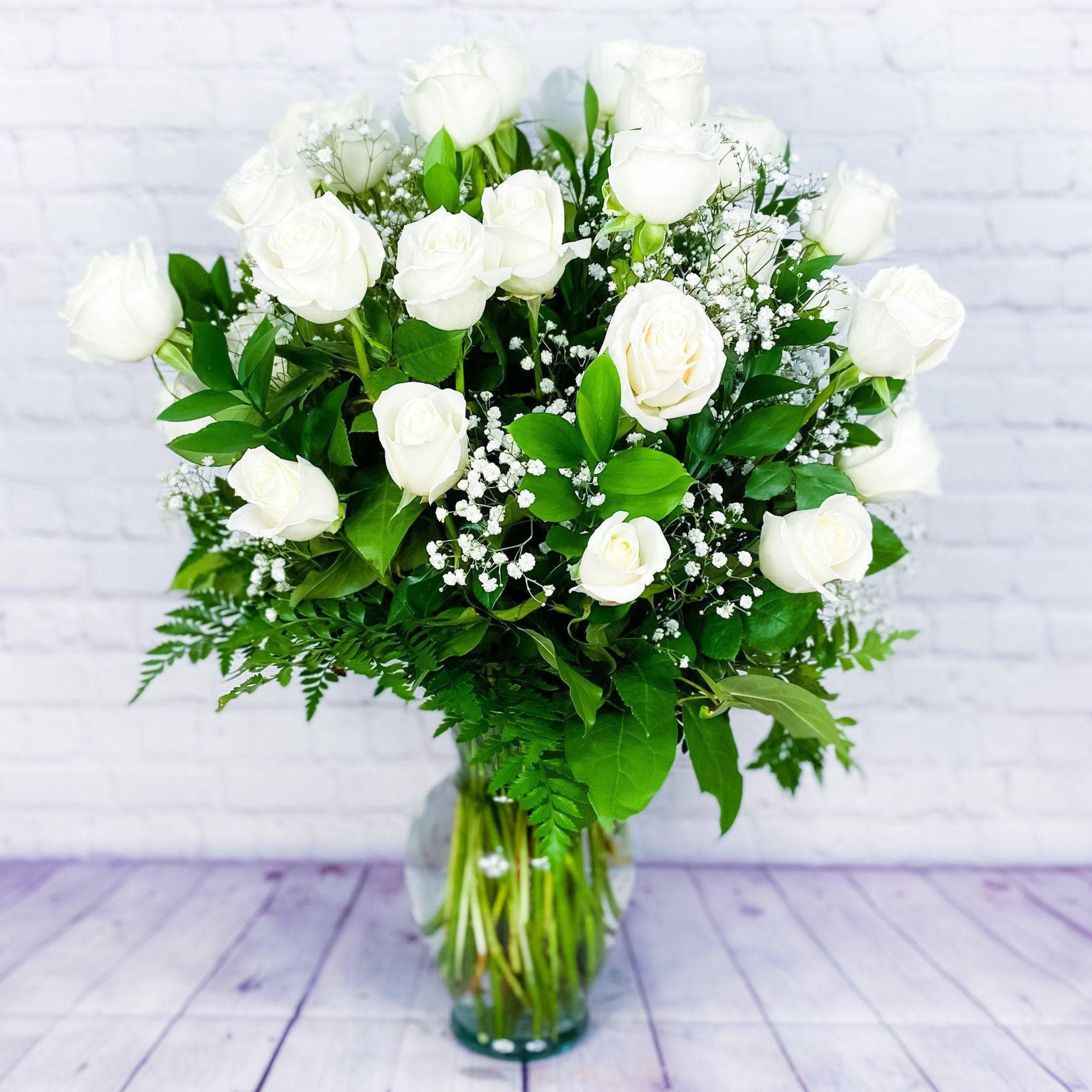 White rose bouquet in a clear glass vase with baby's breath