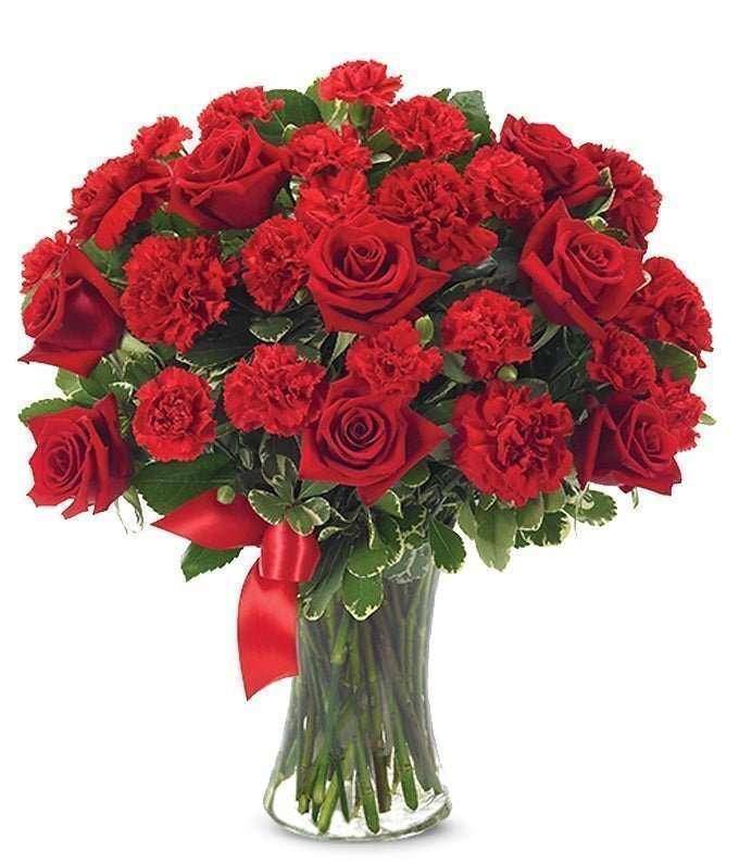 Red roses and carnations in a glass vase with a red ribbon