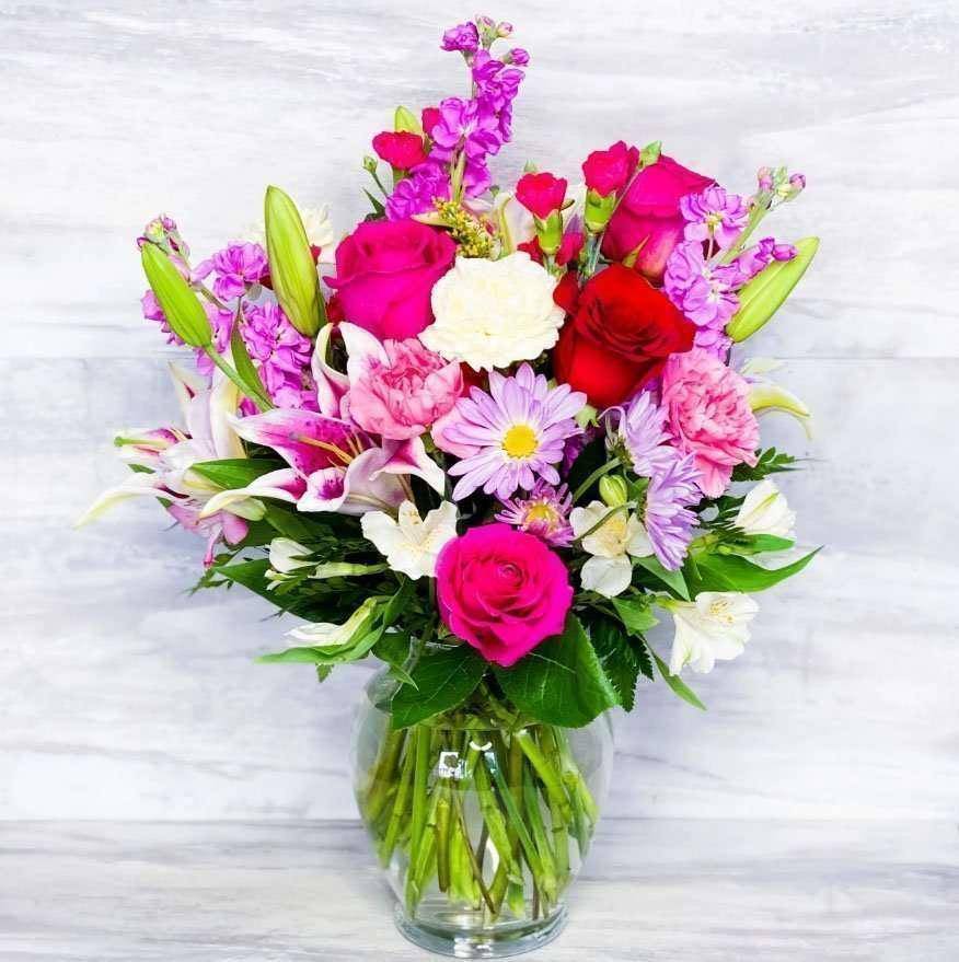 Mixed pink, purple, and white bouquet in a clear glass vase