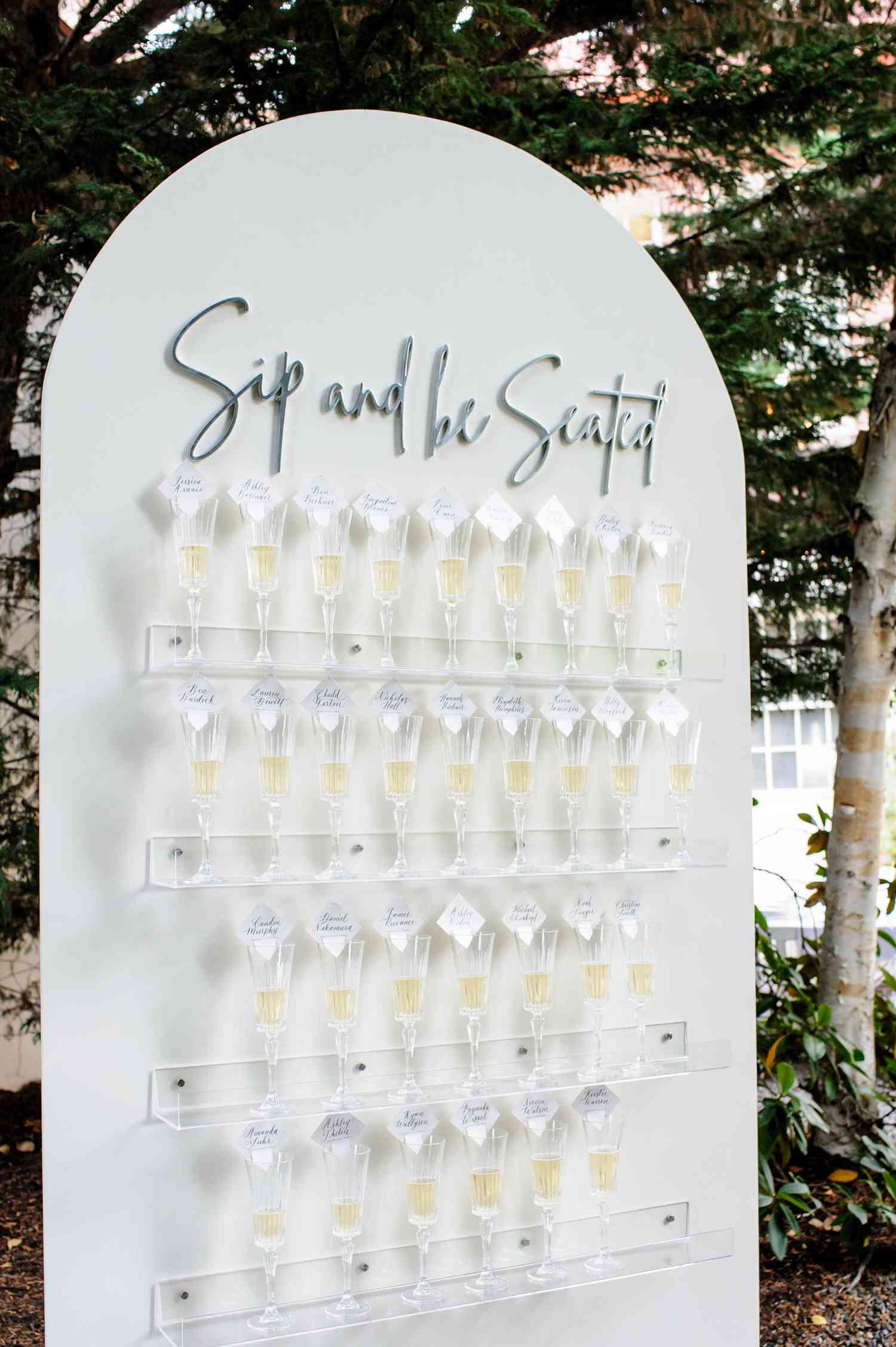 White seating chart board with rows of champagne flutes