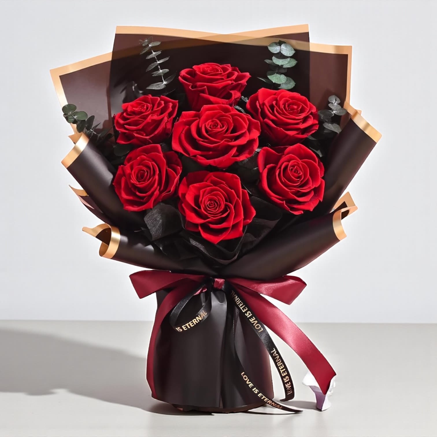 Bouquet of red roses wrapped in dark paper with a burgundy ribbon