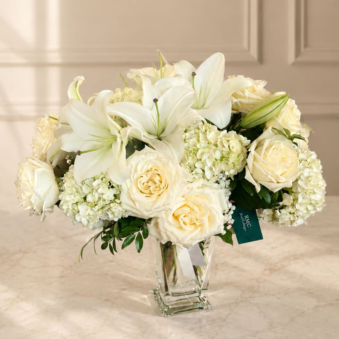 White lilies and cream roses in a clear glass vase