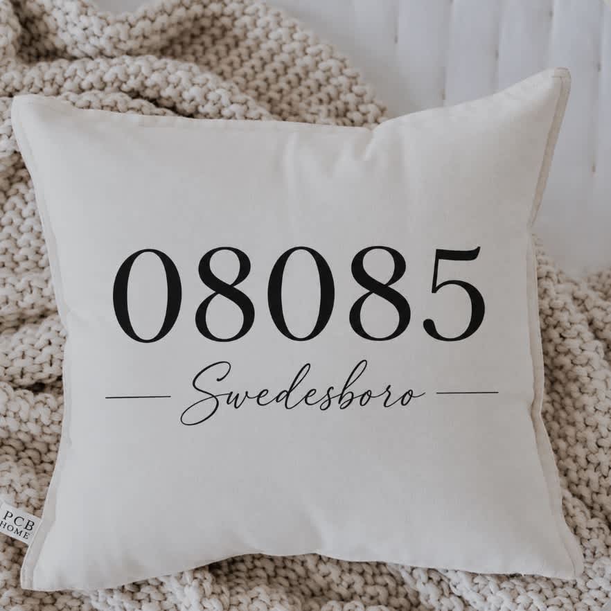 White decorative pillow with black text on a knitted throw