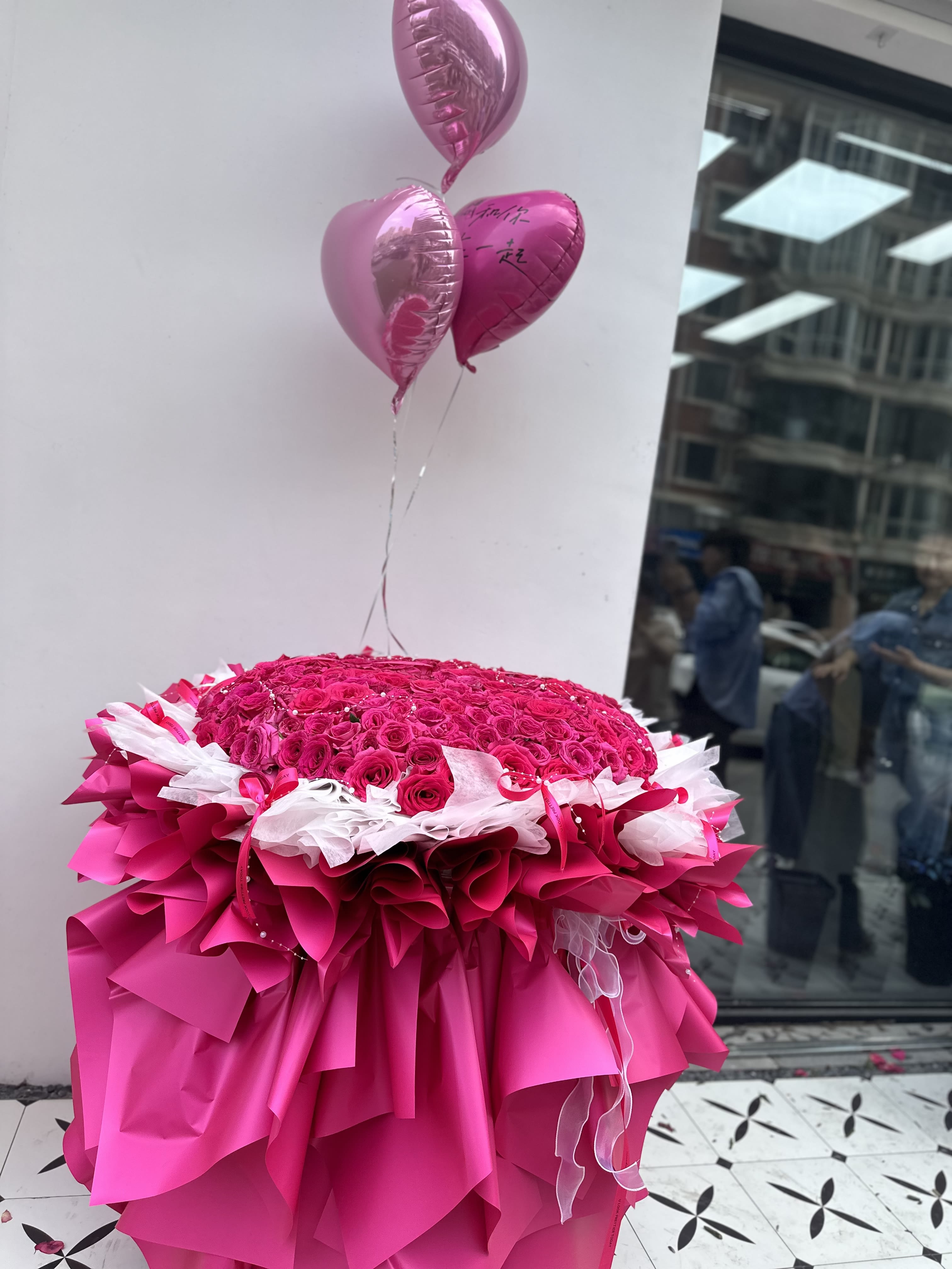 Large pink rose arrangement with heart balloons and layered pink wrapping