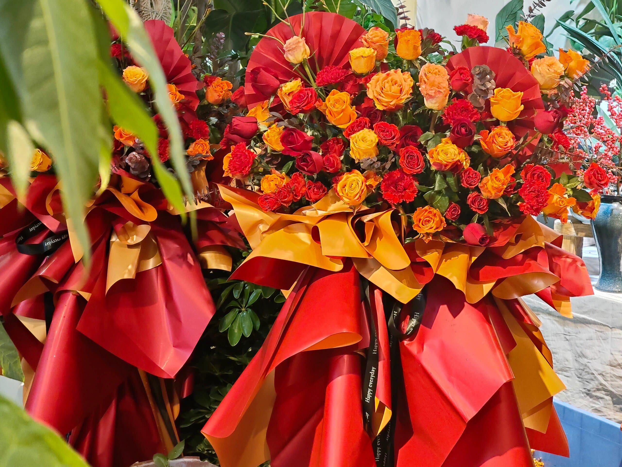 Large bouquet of red, orange, and yellow roses wrapped in red and gold paper