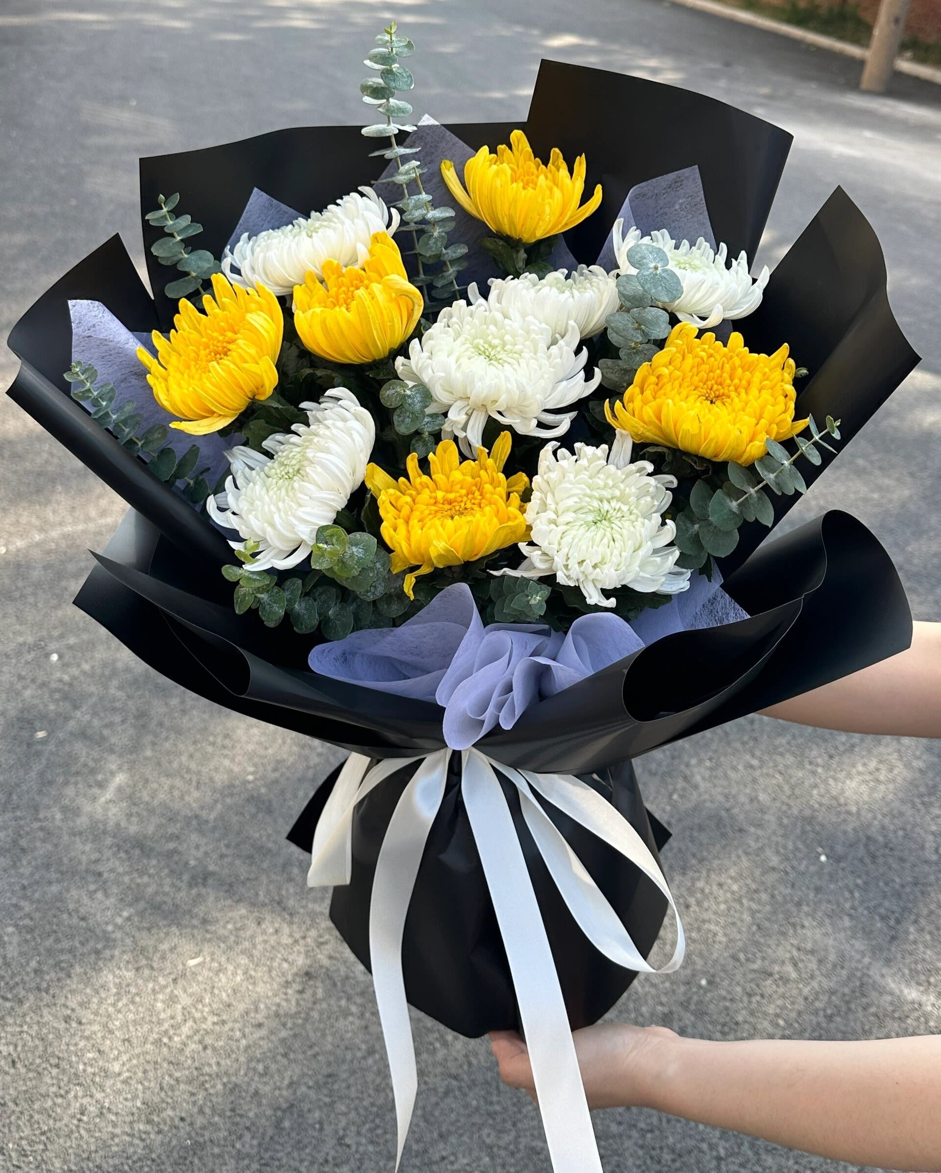 Bouquet of yellow and white chrysanthemums wrapped in black paper