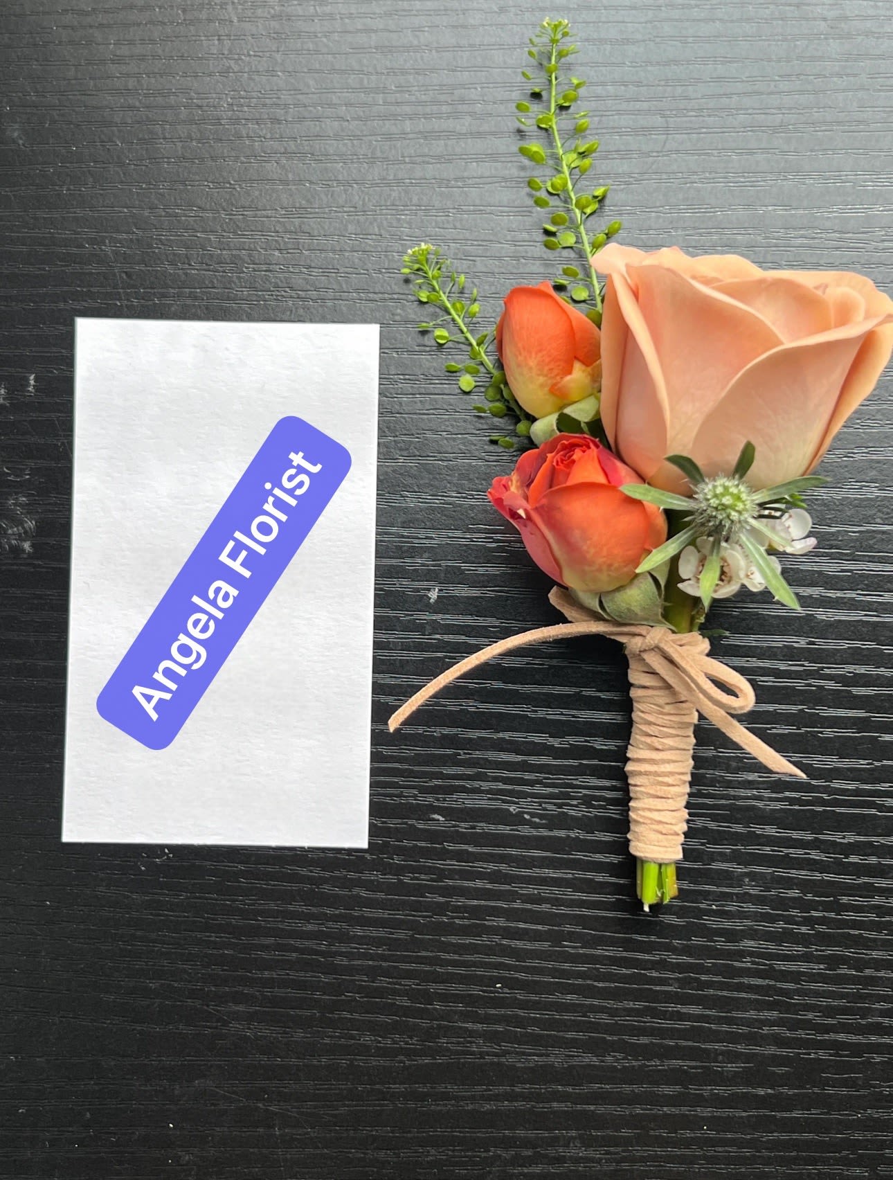 Small boutonniere with peach and orange roses tied with twine