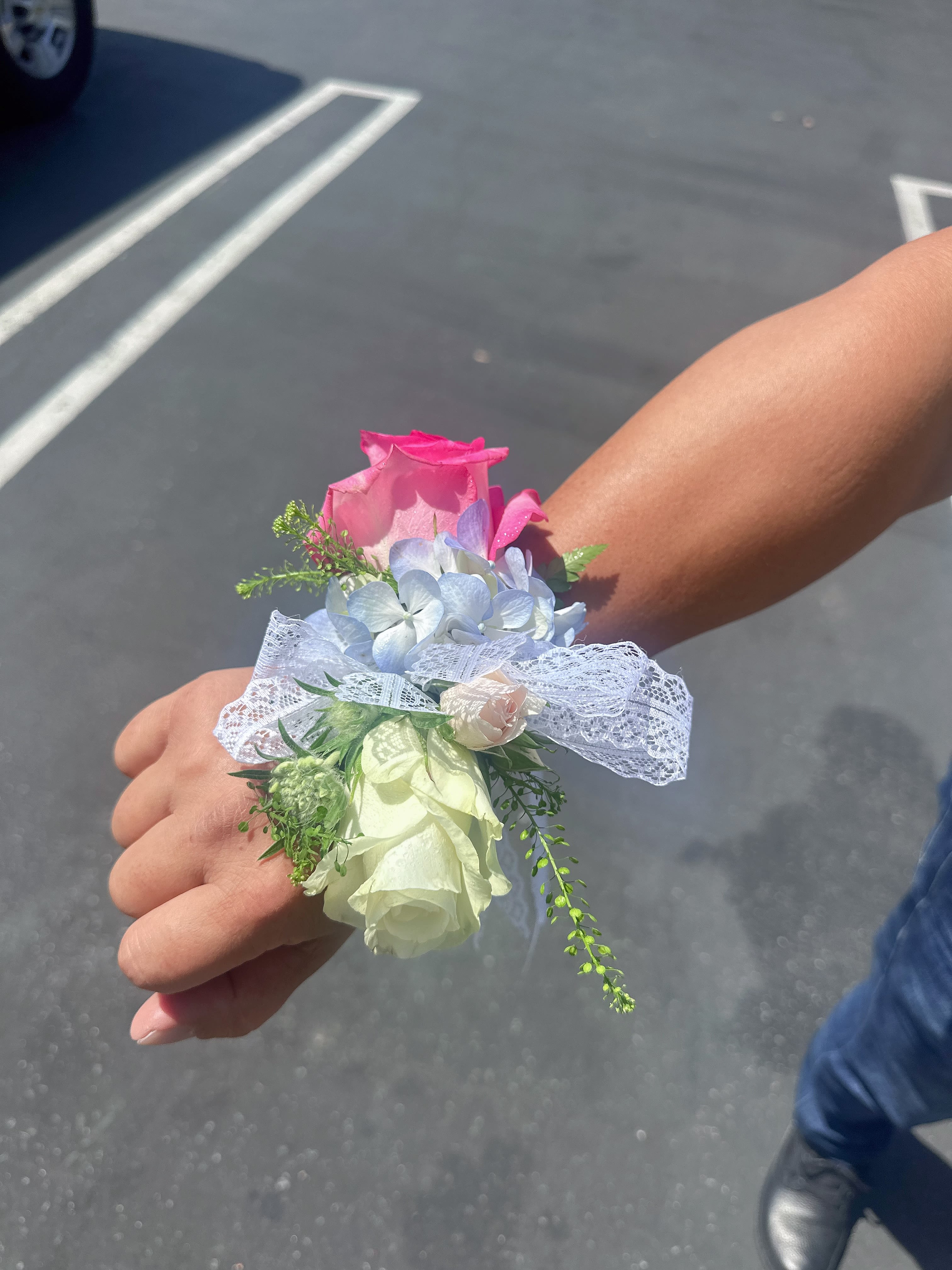 Small wrist corsage with pink and white roses and pale blue flowers