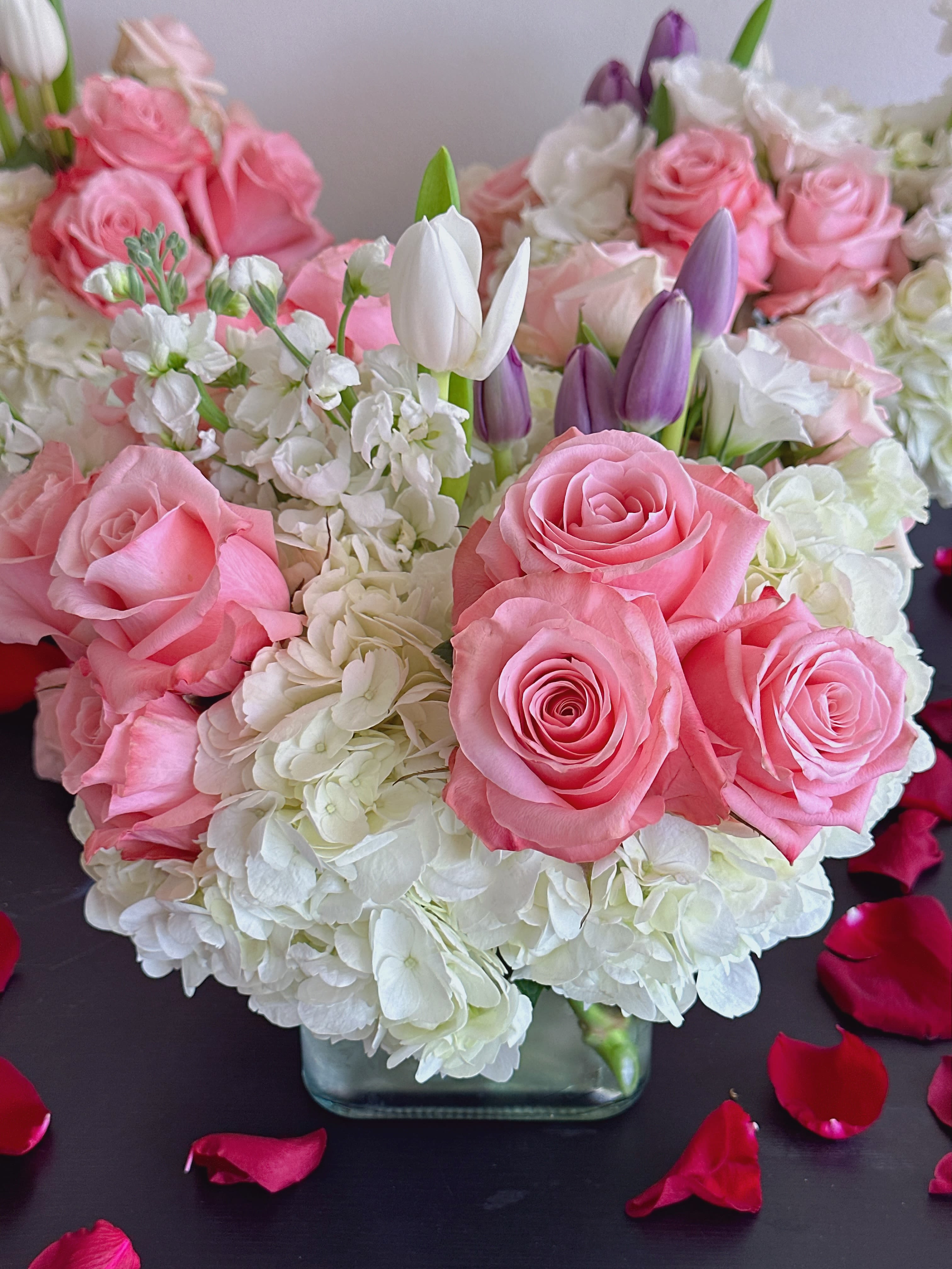Pink roses and white hydrangeas with purple tulips in a glass vase