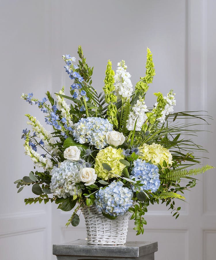 Blue and white floral arrangement in a white wicker basket