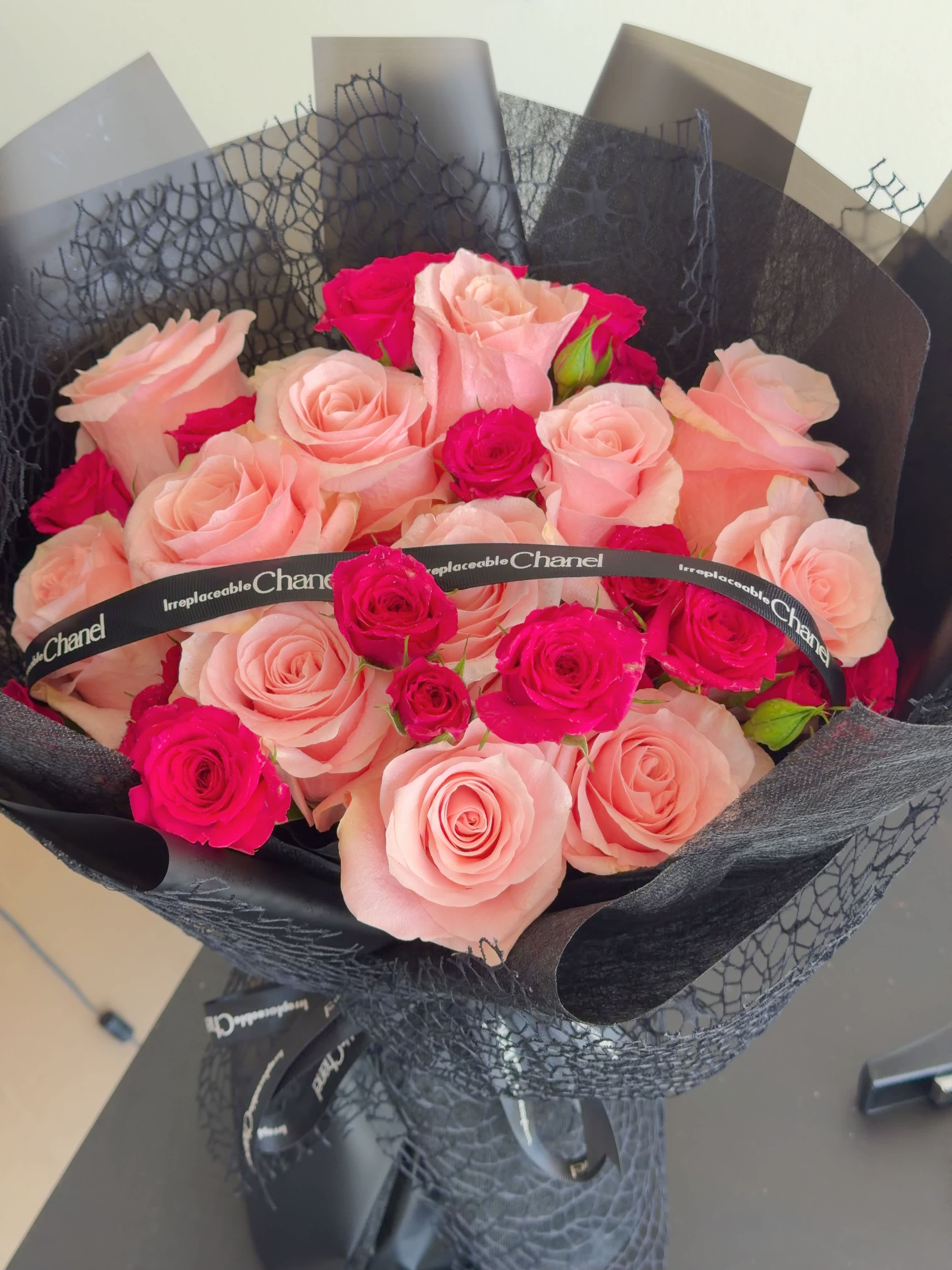 Bouquet of pale pink and hot pink roses wrapped in black paper