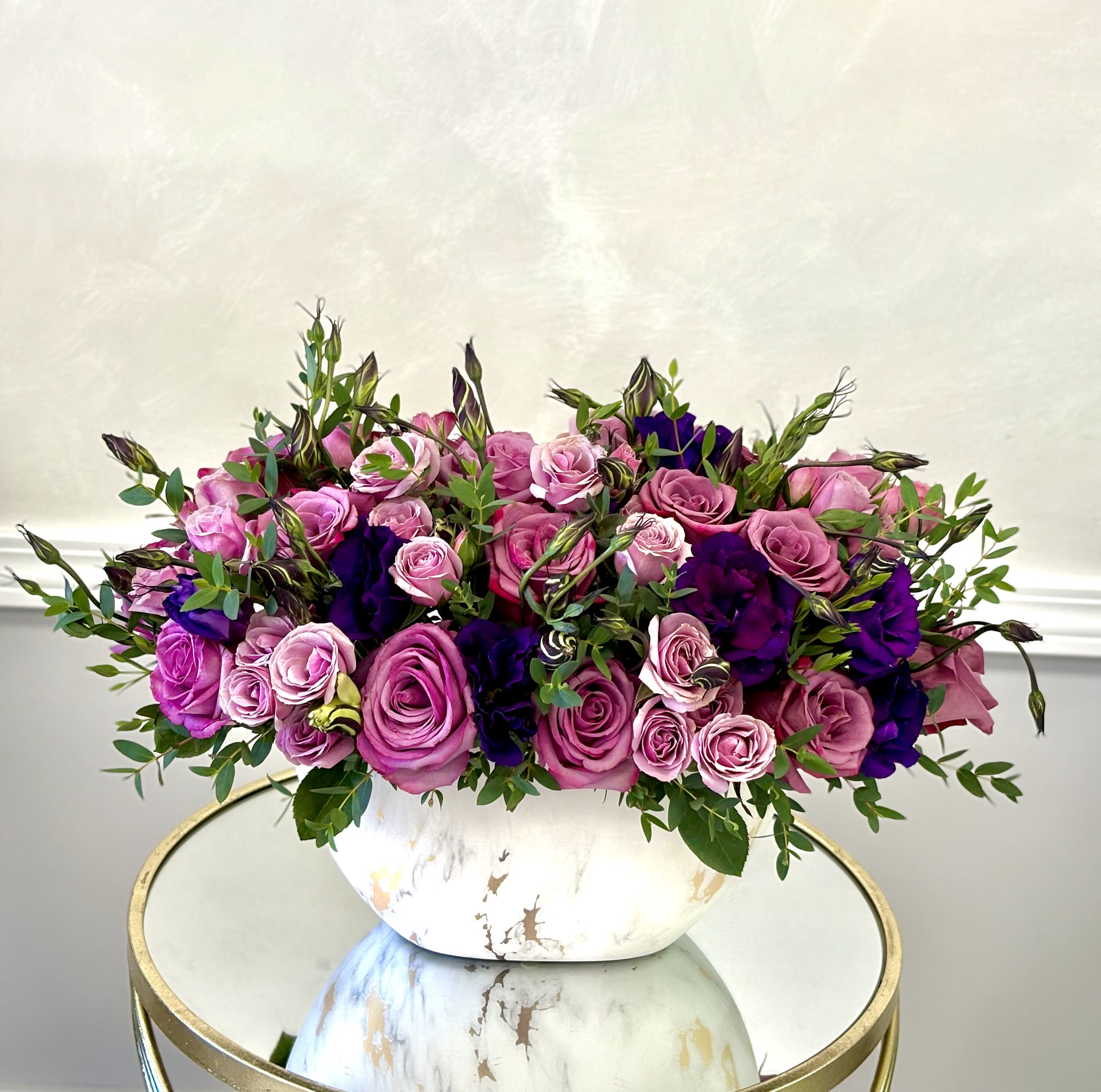 Purple Romance By VLM Flowers - A lush mound of pink roses and deep purple blooms creates an immediate romantic impression-perfect as a birthday bouquet, anniversary roses, or a "just because" surprise for someone you adore. The color story of pink, purple, and green reads both vibrant and intimate, so the person you're thinking of will feel genuinely celebrated the moment this arrangement arrives. 