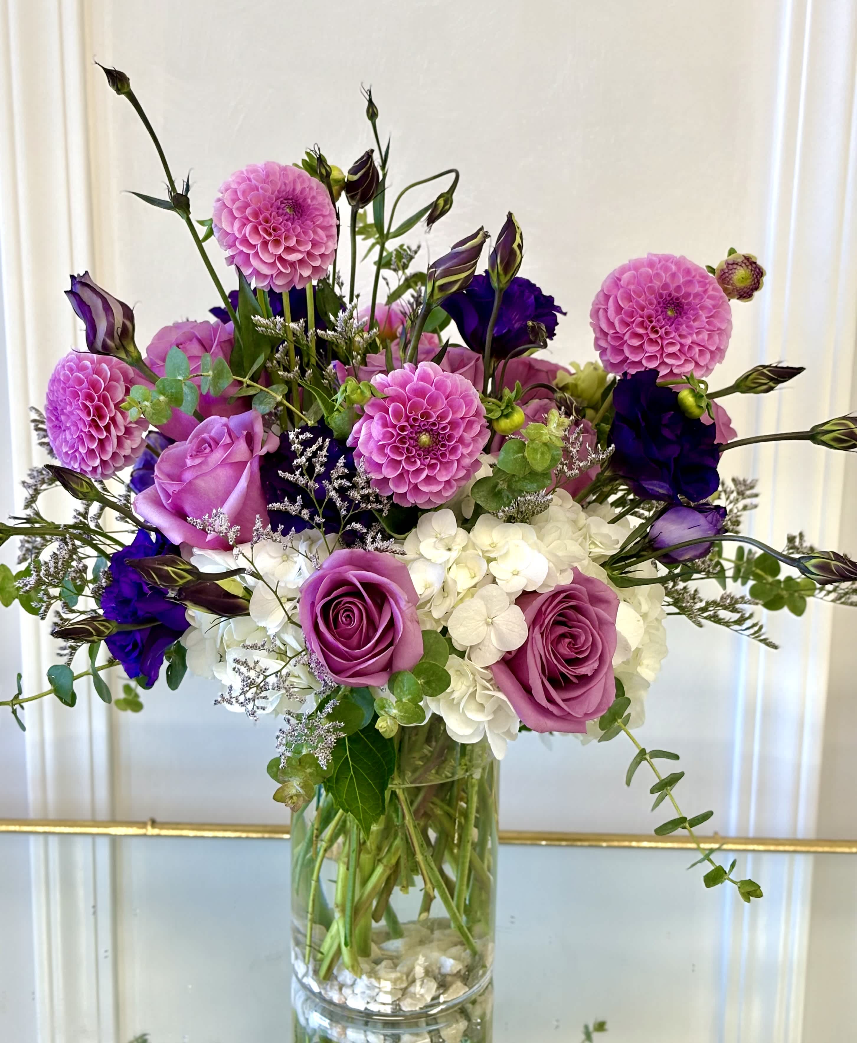 Pink and purple bouquet with roses, dahlias, and white hydrangeas in a glass vase