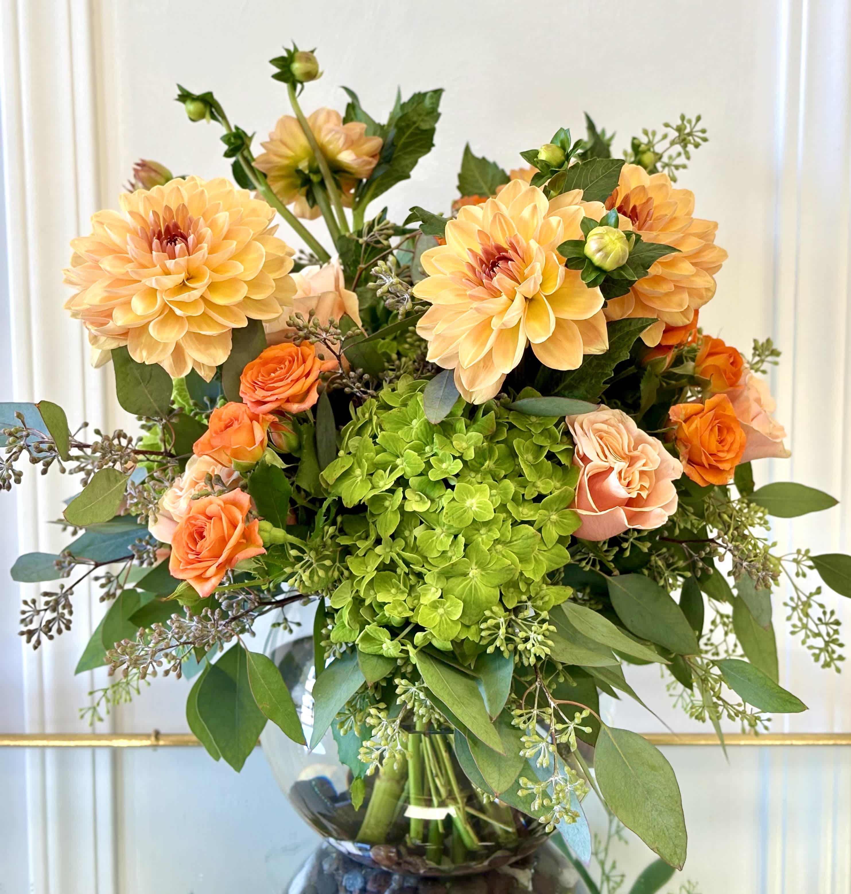 Bouquet of peach dahlias and orange roses in a glass vase