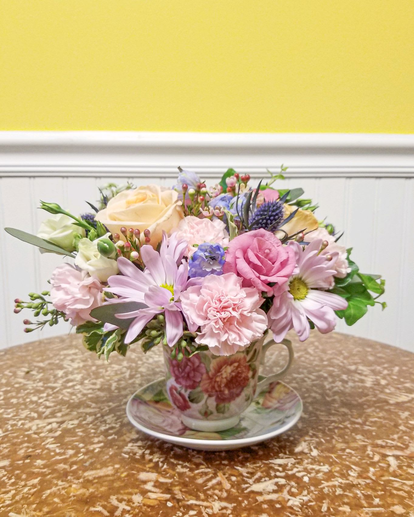 Pastel flower arrangement in a floral teacup and saucer