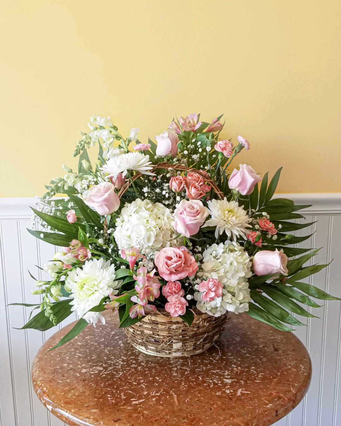 Pink and white mixed flower arrangement in a wicker basket