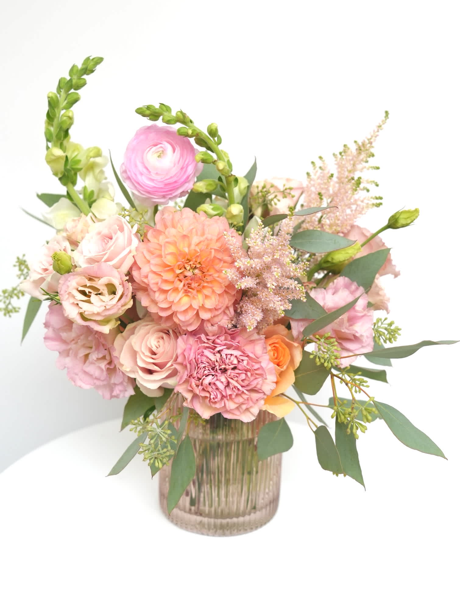 Pink and peach floral arrangement in a ribbed glass vase