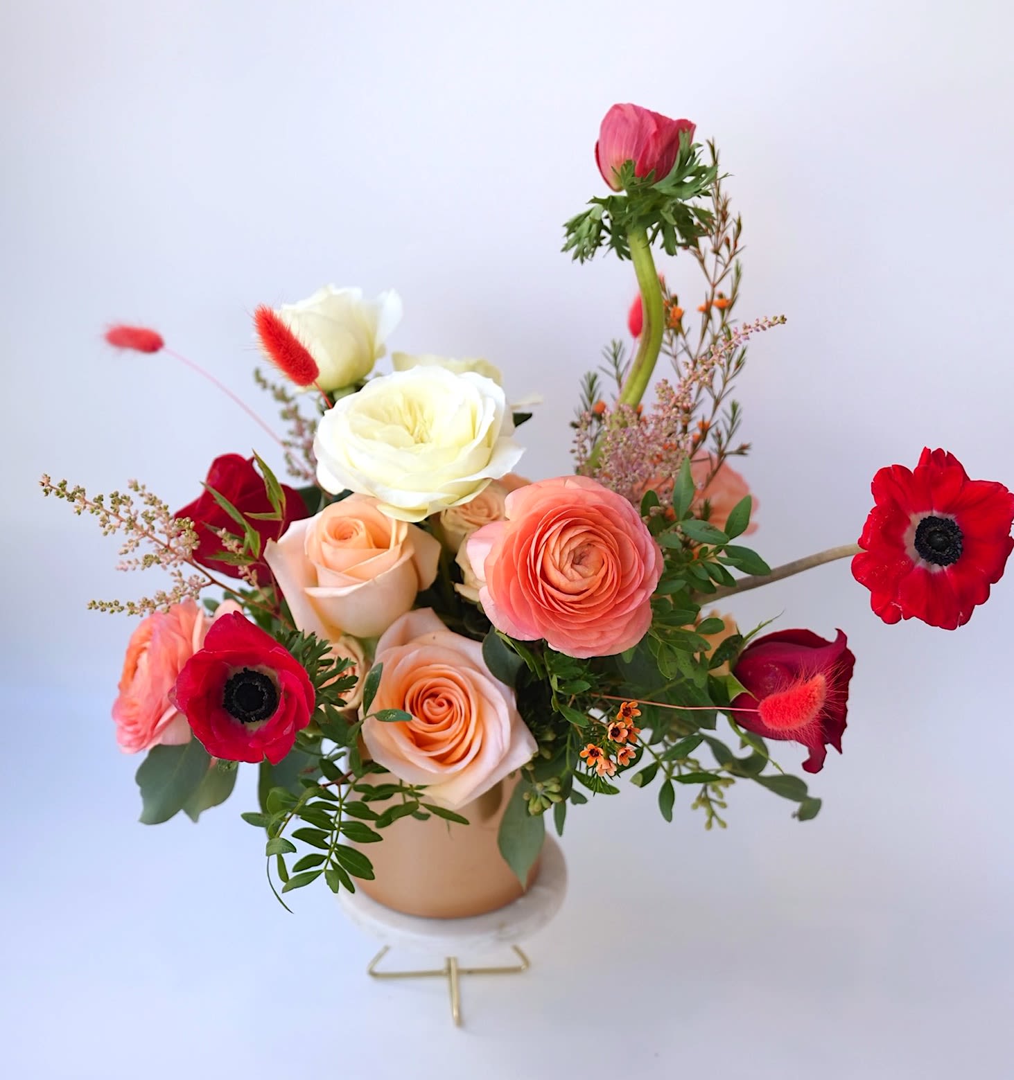 Mixed bouquet of roses and red anemones in a small vase