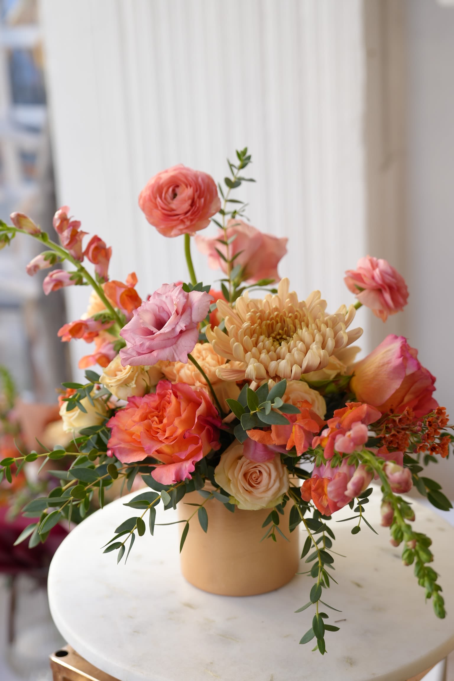 Peach and pink mixed bouquet in a tan vase