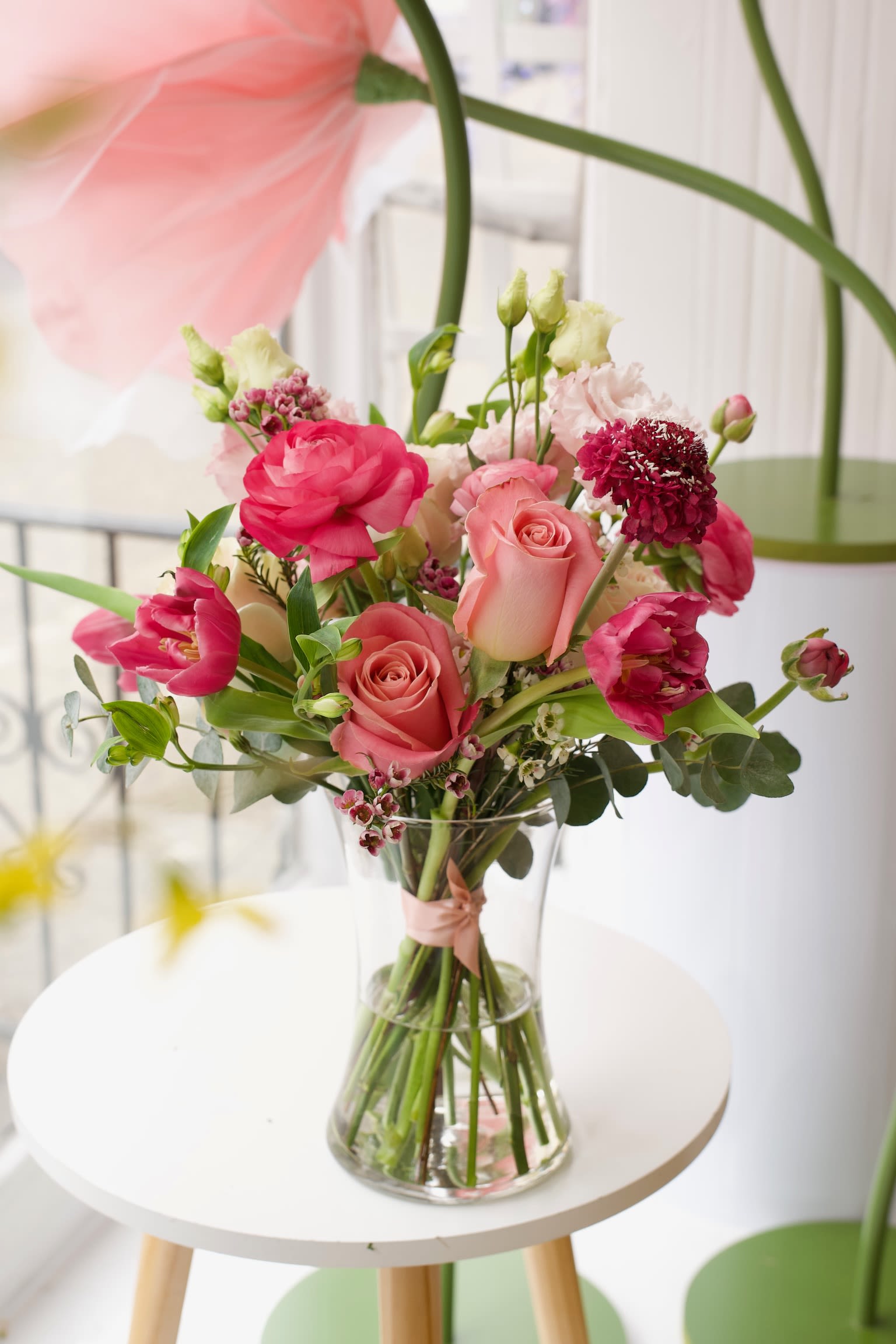 Pink and coral bouquet of roses and tulips in a clear glass vase