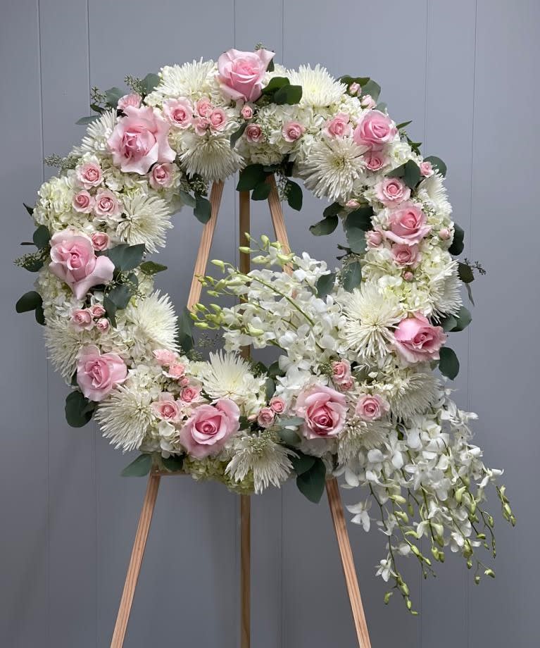 Pink and white floral wreath on a wooden easel